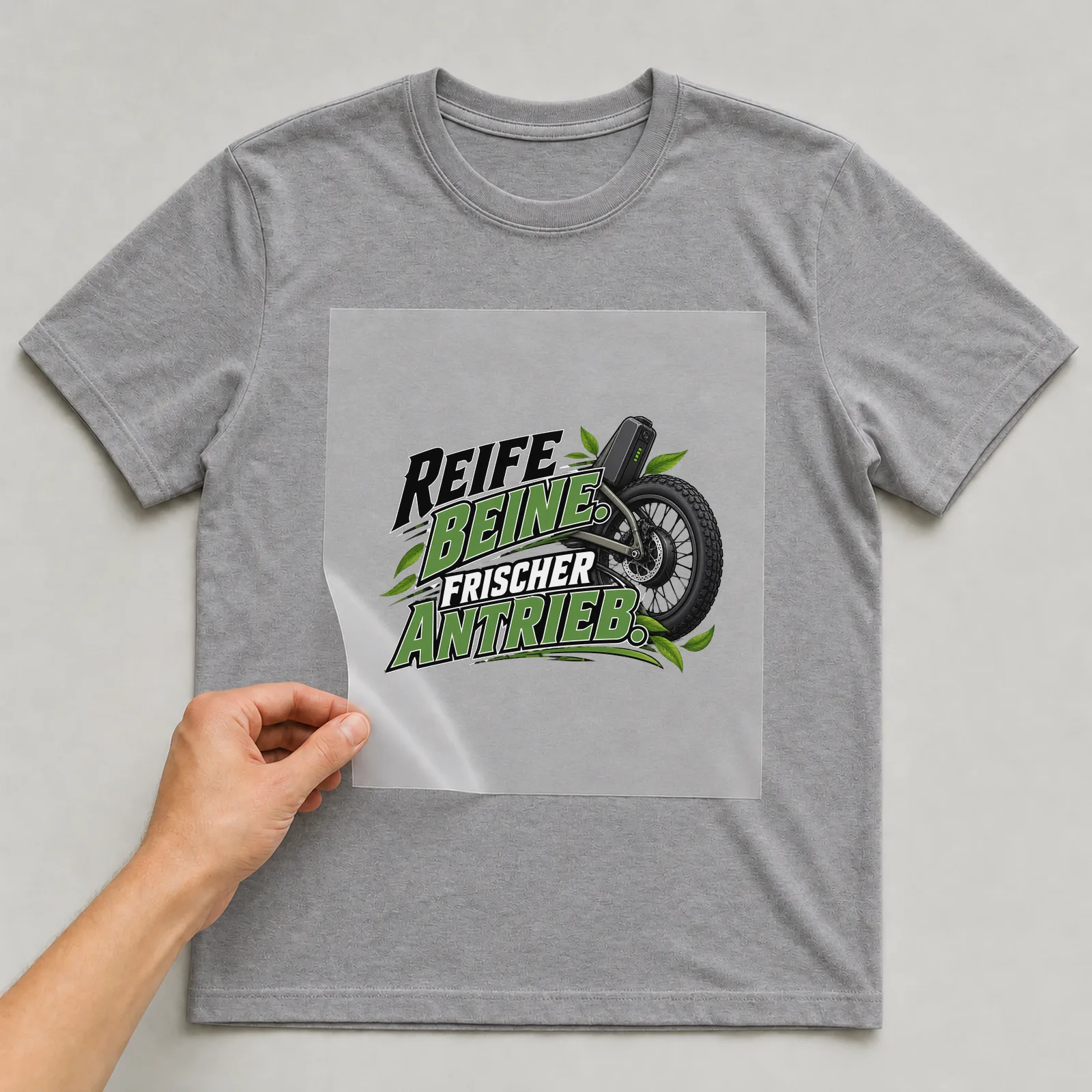 Bügelbild „Reife Beine. Frischer antrieb.“ auf grauem T-Shirt, Folie wird aufgelegt