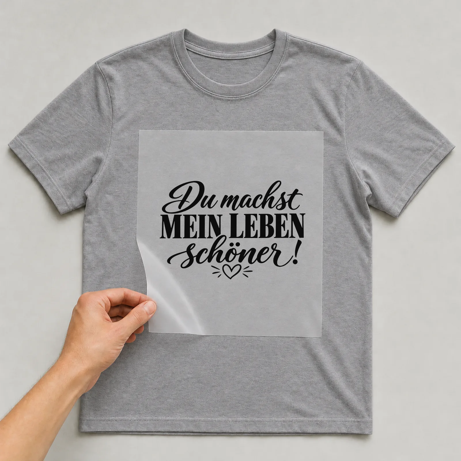 Bügelbild „Du machst mein Leben schöner!“ auf grauem T-Shirt, Folie wird aufgelegt