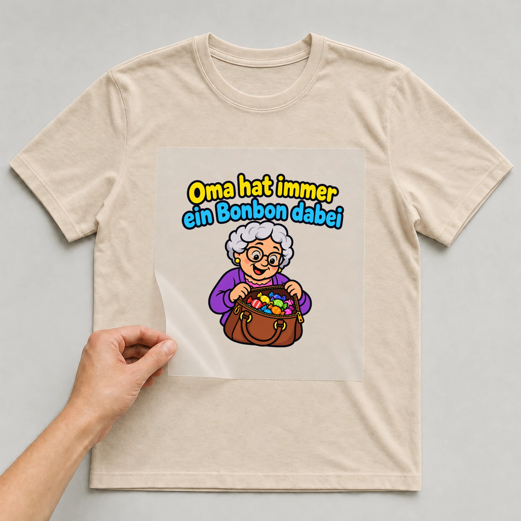 Bügelbild „Oma hat immer ein Bonbon dabei“ auf beigem T-Shirt, Folie wird aufgelegt