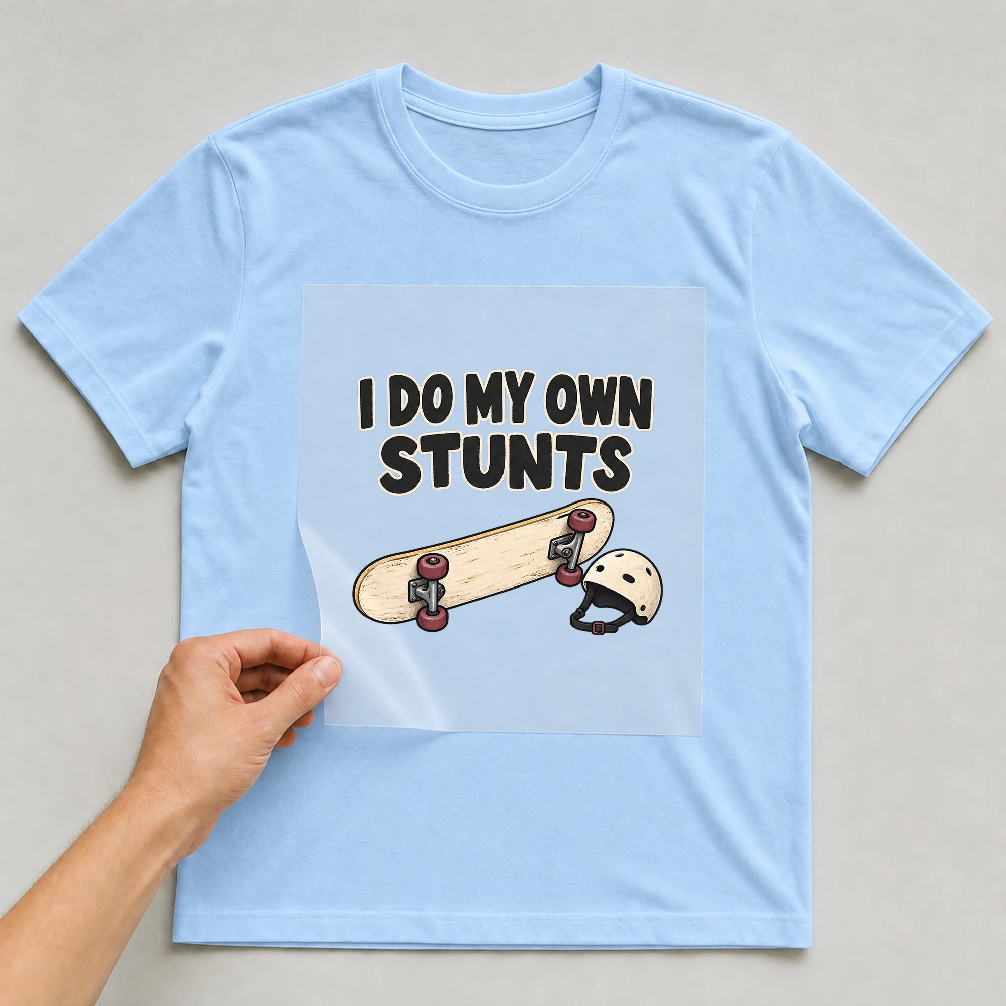 Bügelbild „I DO MY OWN STUNTS“ auf babyblauem T-Shirt, Folie wird aufgelegt