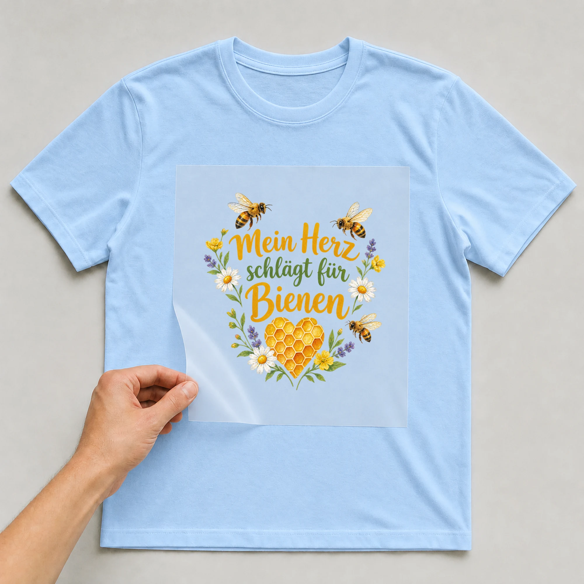 Bügelbild „Mein Herz schlägt für Bienen“ auf babyblauem T-Shirt, Folie wird aufgelegt