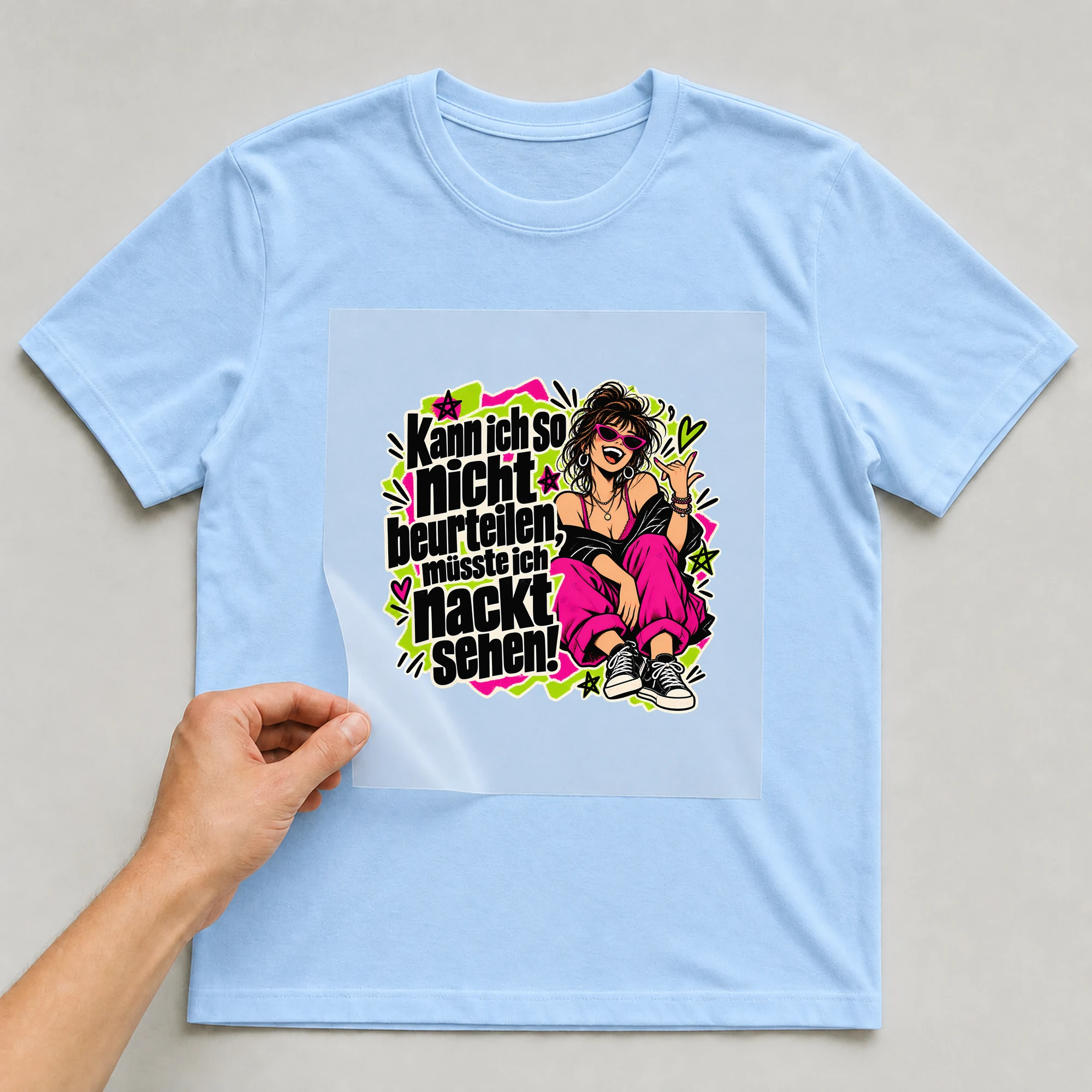 Bügelbild „Kann ich so nicht beurteilen, müsste ich nackt sehen!“ auf babyblauem T-Shirt, Folie wird aufgelegt