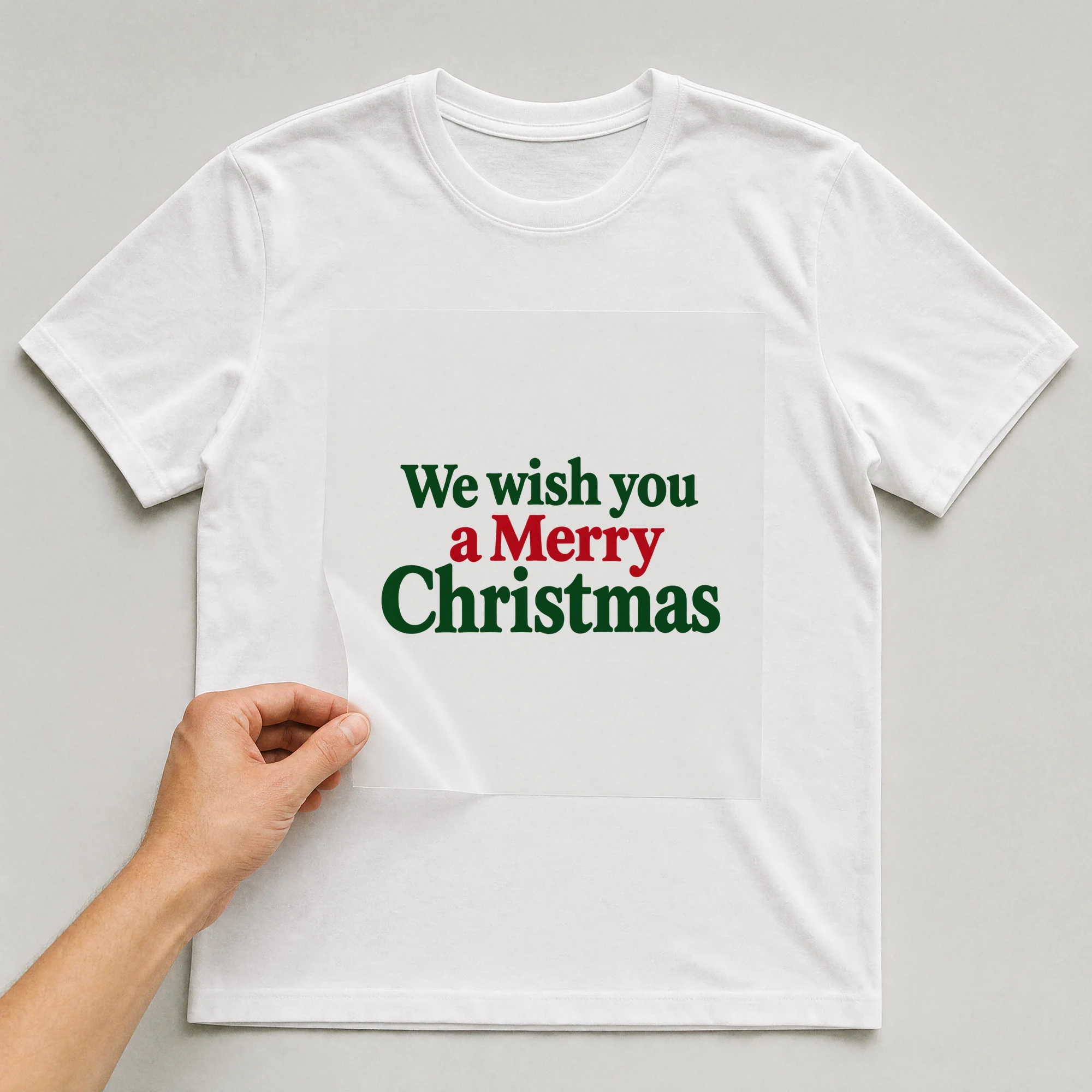 Bügelbild „We wish you a Merry Christmas“ auf weißem T-Shirt, Folie wird aufgelegt