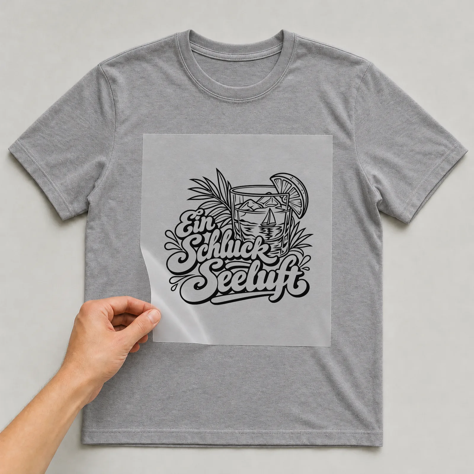 Bügelbild „Ein Schluck Seeluft“ auf grauem T-Shirt, Folie wird aufgelegt