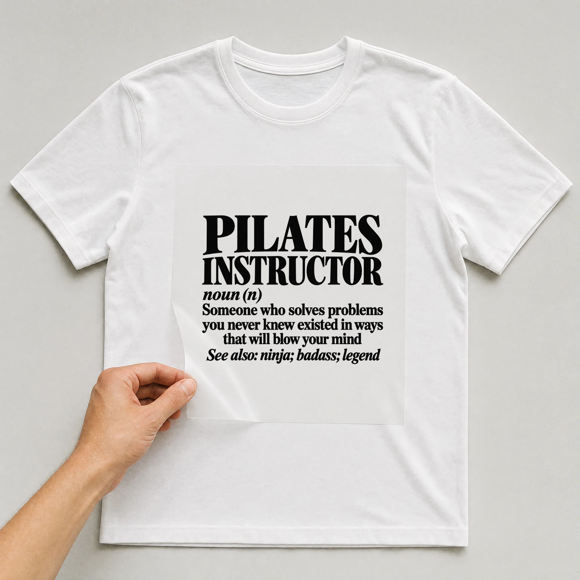 Bügelbild „Pilates Instructor Noun (n) Someone Who Solves Problems You Never Knew Existed“ auf weißem T-Shirt, Folie wird aufgelegt