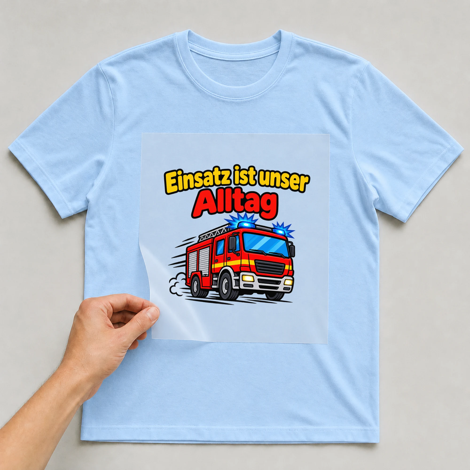 Bügelbild „Einsatz ist unser Alltag“ auf babyblauem T-Shirt, Folie wird aufgelegt