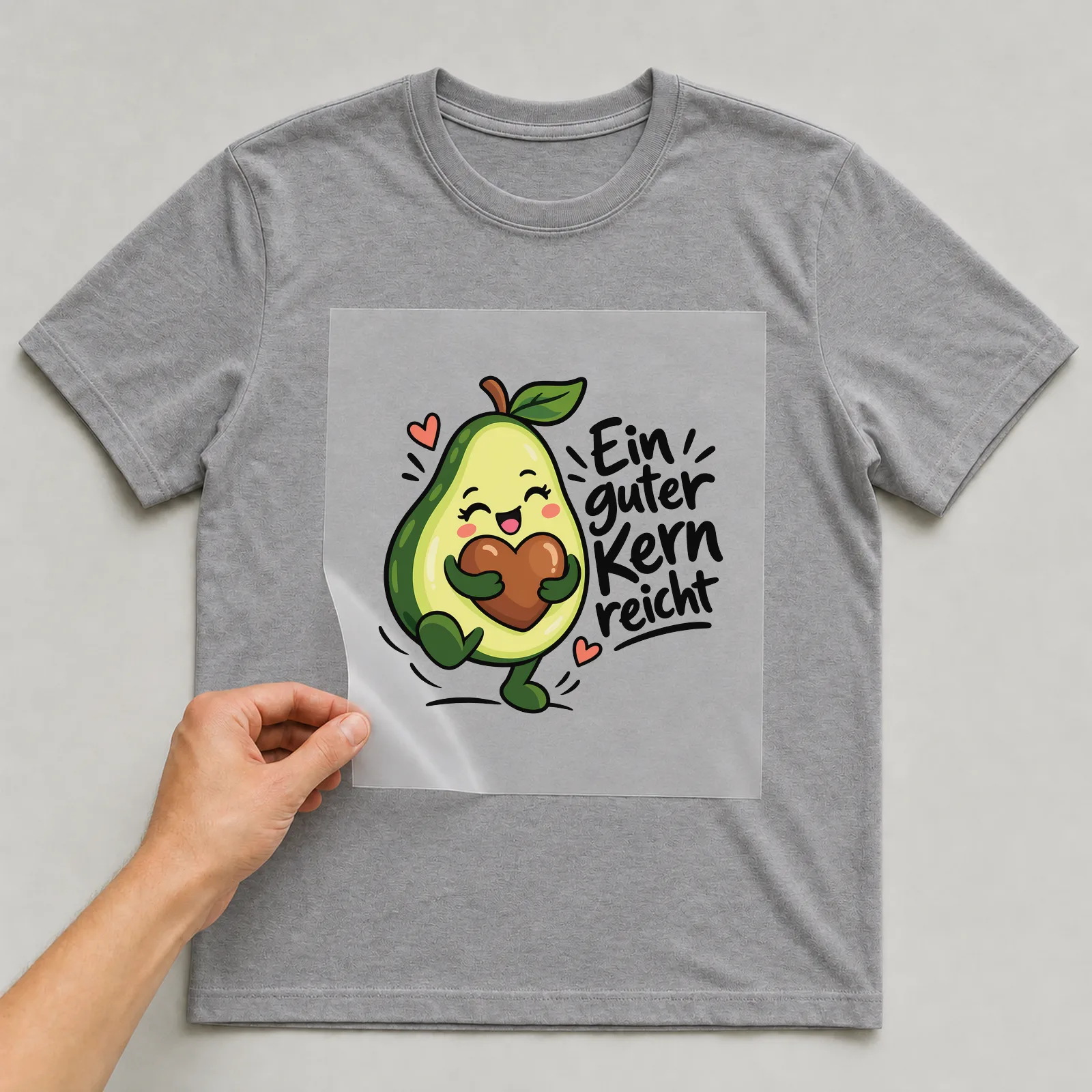 Bügelbild „Ein guter Kern reicht“ auf grauem T-Shirt, Folie wird aufgelegt