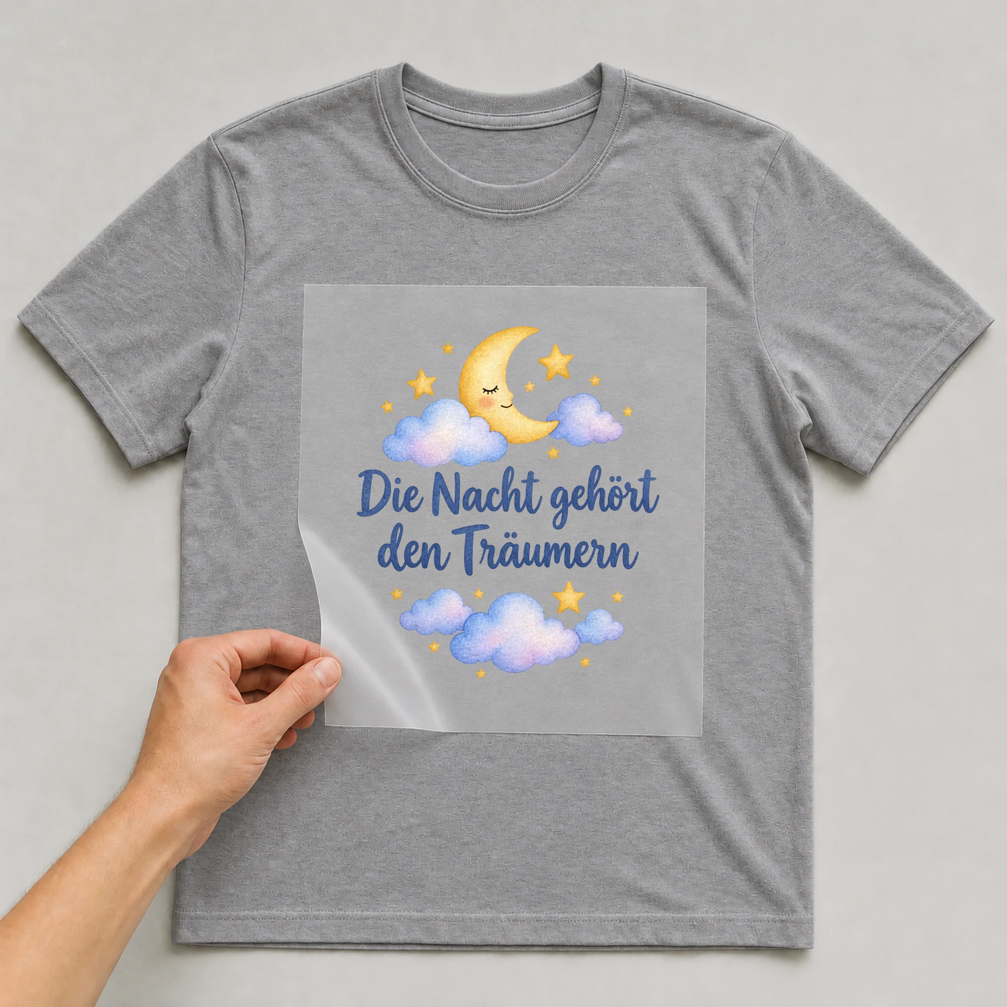 Bügelbild „Die Nacht gehört den Träumern“ auf grauem T-Shirt, Folie wird aufgelegt