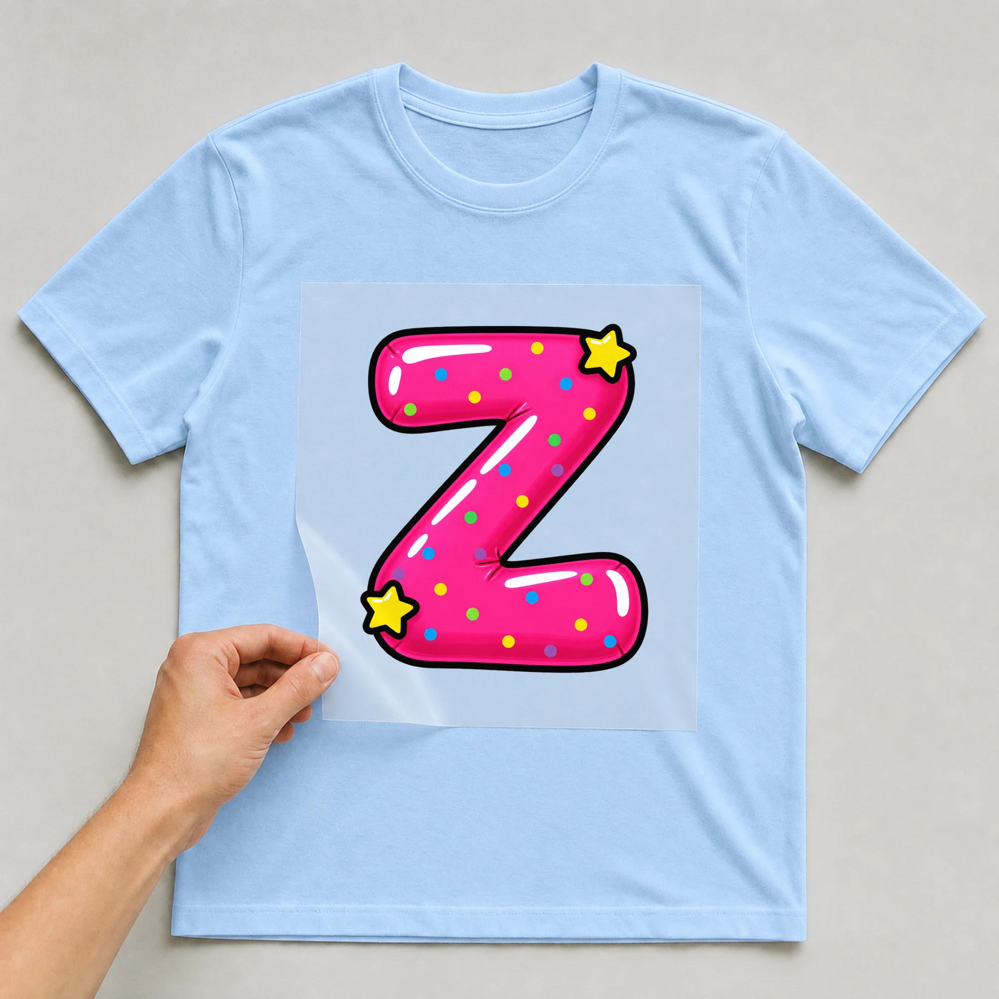 Bügelbild „Buchstabe Z im Comic-Ballon-Stil“ auf babyblauem T-Shirt, Folie wird aufgelegt