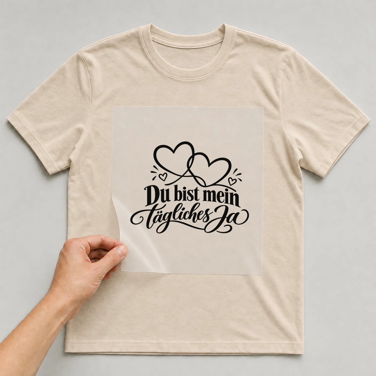 Bügelbild „Du bist mein tägliches Ja“ auf beigem T-Shirt, Folie wird aufgelegt