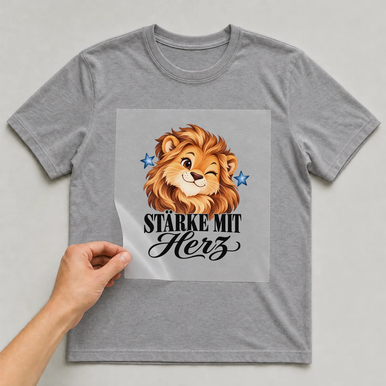 Bügelbild „Stärke mit Herz“ auf grauem T-Shirt, Folie wird aufgelegt