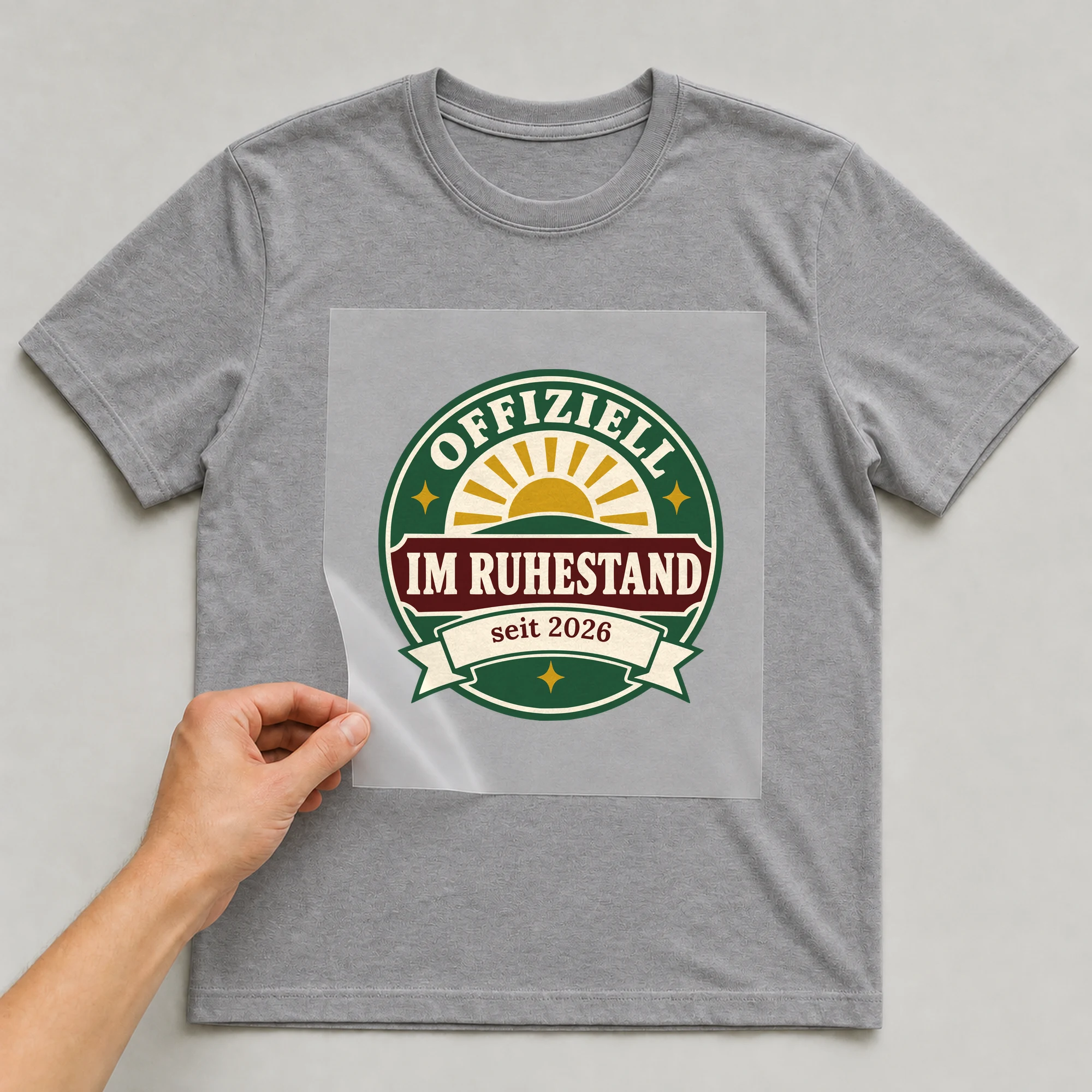 Bügelbild Offiziell im Ruhestand mit Jahr auf grauem T-Shirt, Folie wird aufgelegt