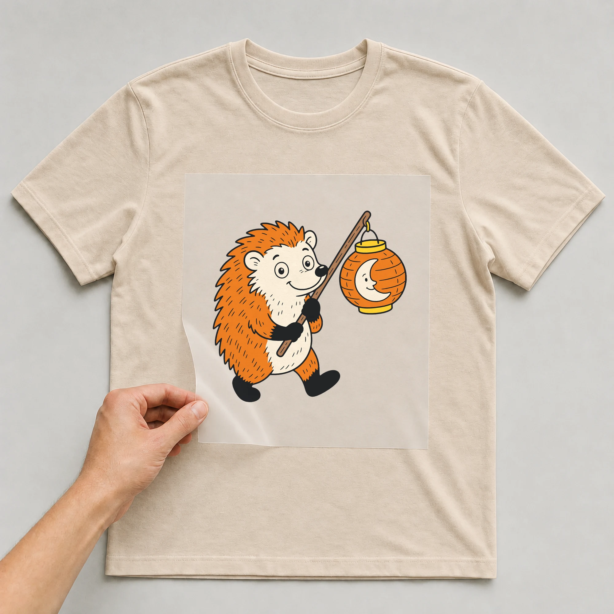 Bügelbild „Igel mit Laterne“ auf beigem T-Shirt, Folie wird aufgelegt