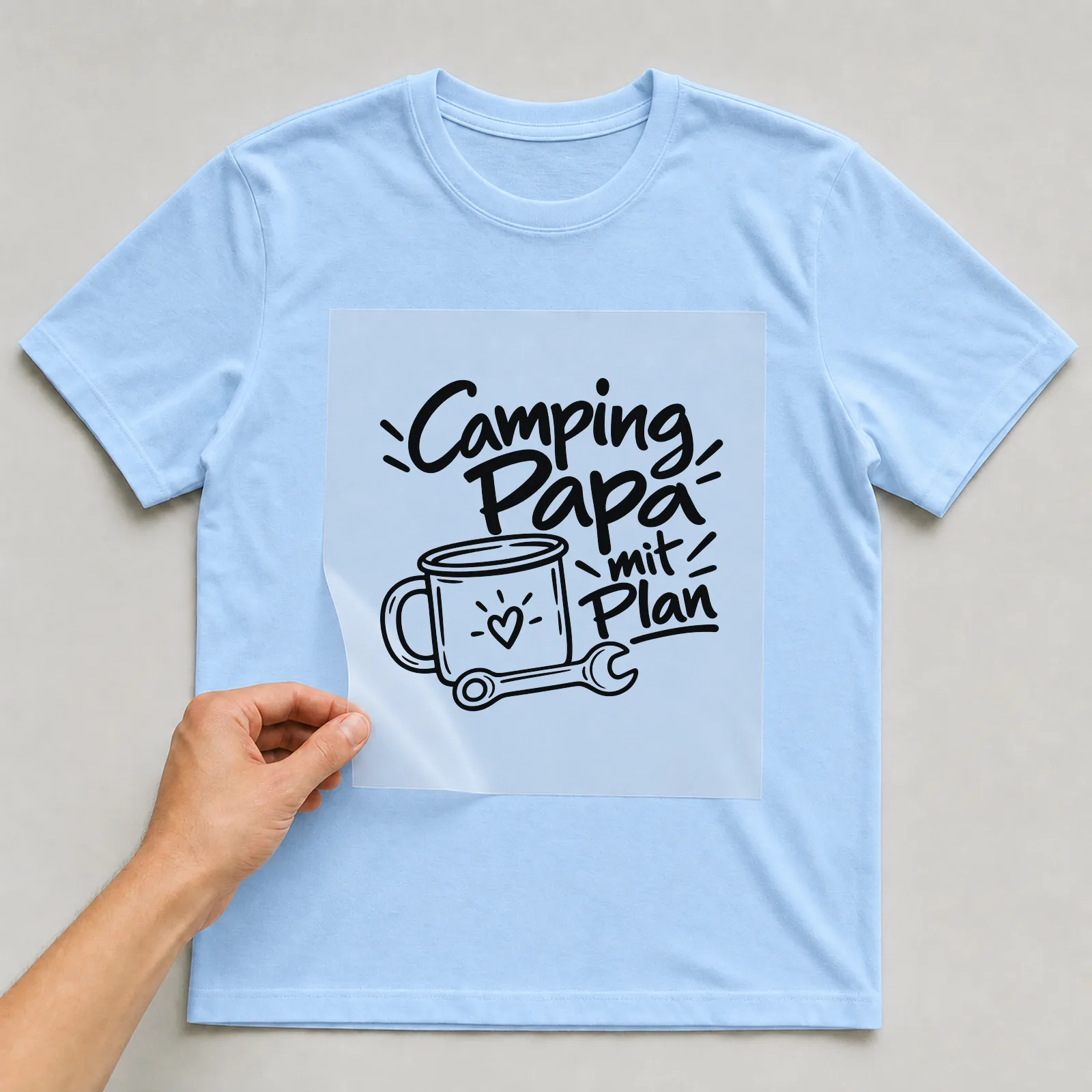 Bügelbild „Camping Papa mit Plan“ auf hellblauem T-Shirt, Folie wird aufgelegt