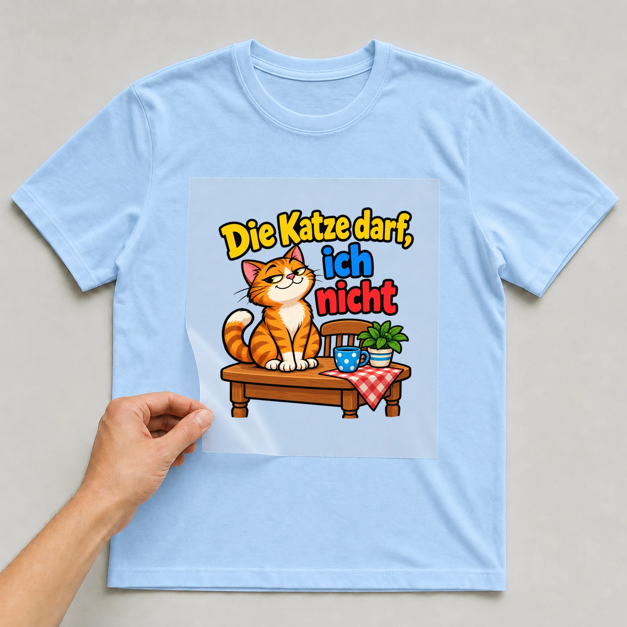 Bügelbild „Die Katze darf, ich nicht“ auf babyblauem T-Shirt, Folie wird aufgelegt