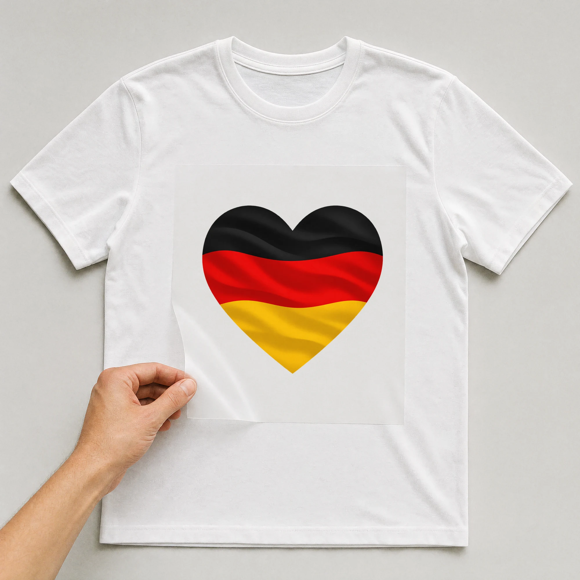 Bügelbild „Herz-Flagge Deutschland“ auf weißem T-Shirt, Folie wird aufgelegt