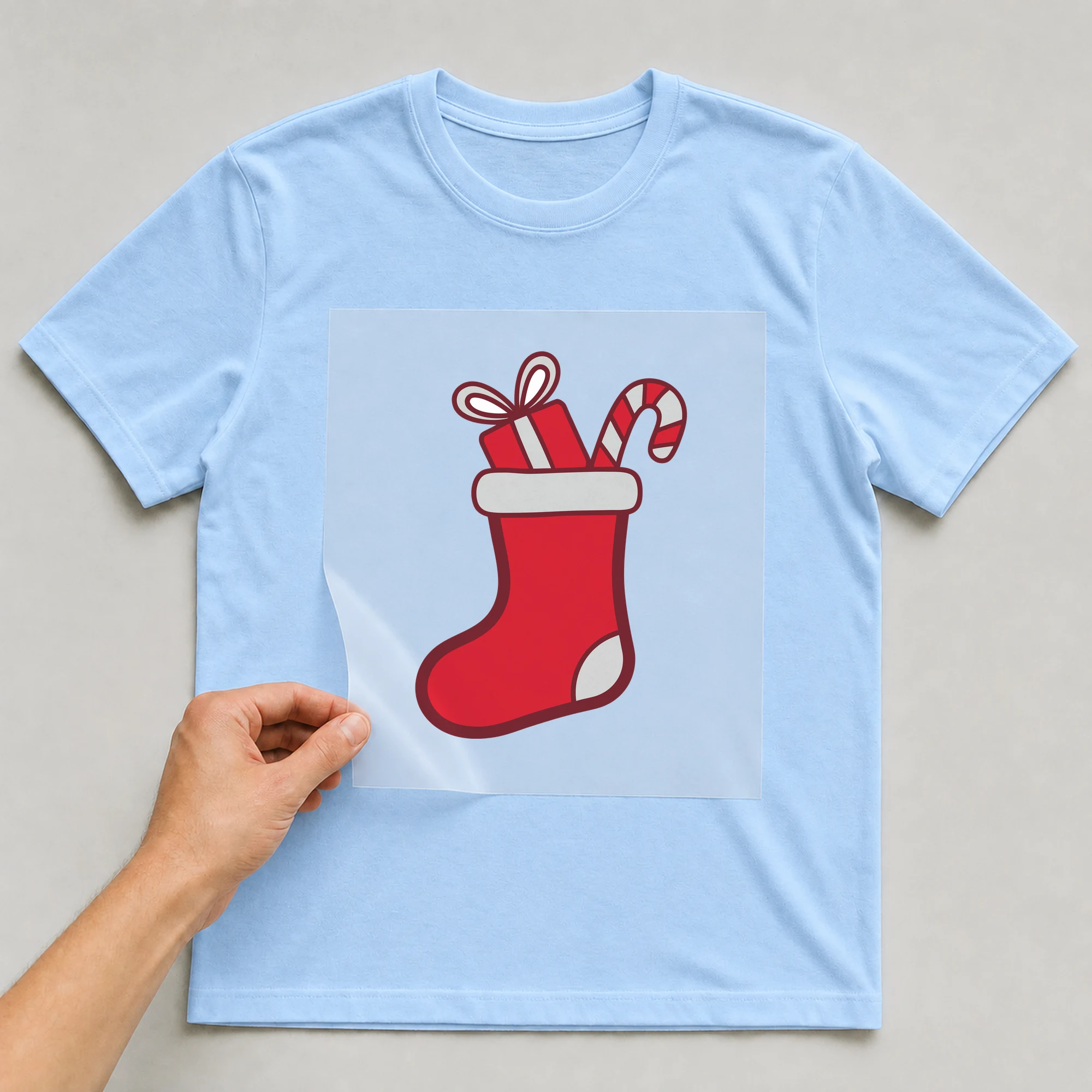 Bügelbild „Nikolausstrumpf“ auf babyblauem T-Shirt, Folie wird aufgelegt