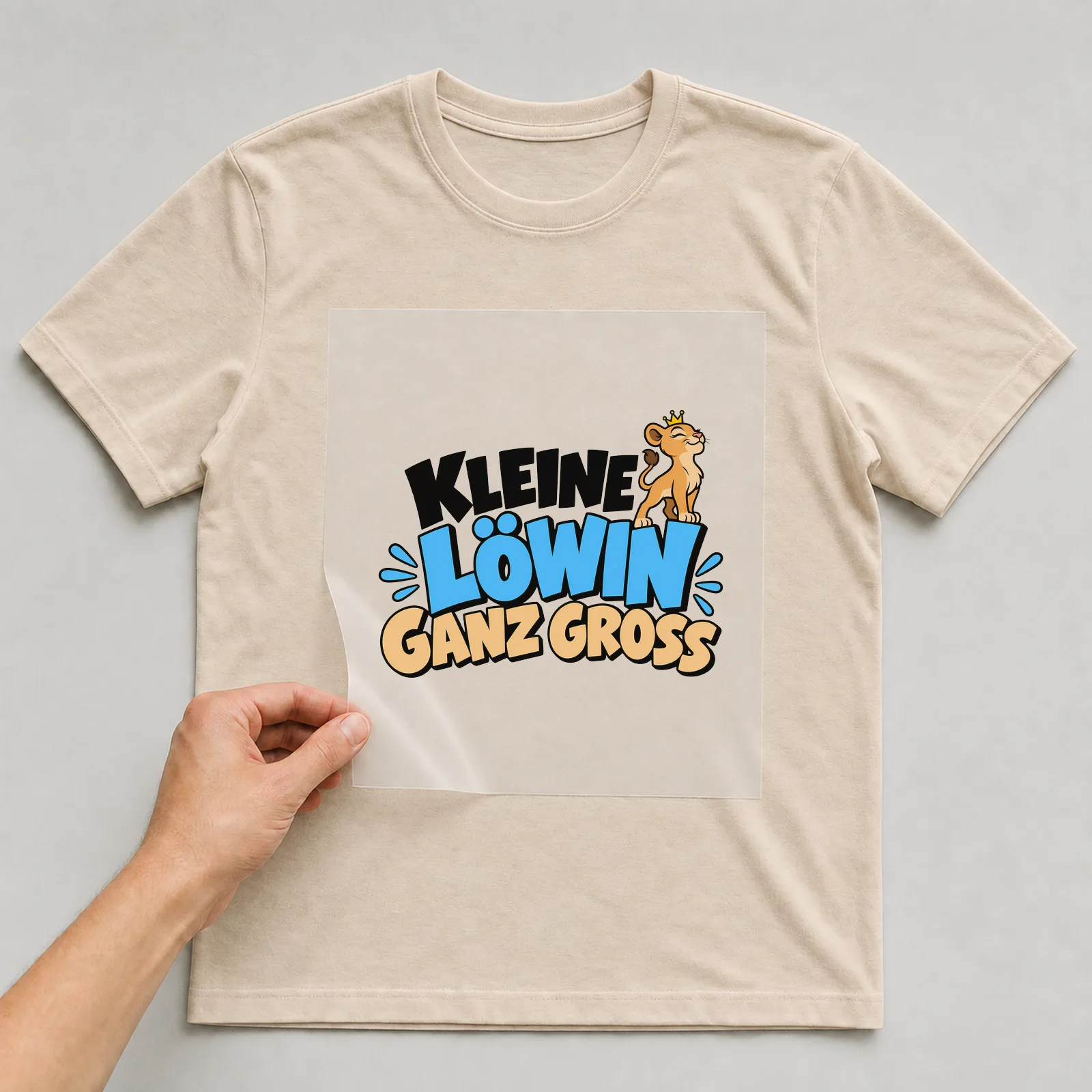 Bügelbild „Kleine Löwin ganz groß“ auf beigem T-Shirt, Folie wird aufgelegt