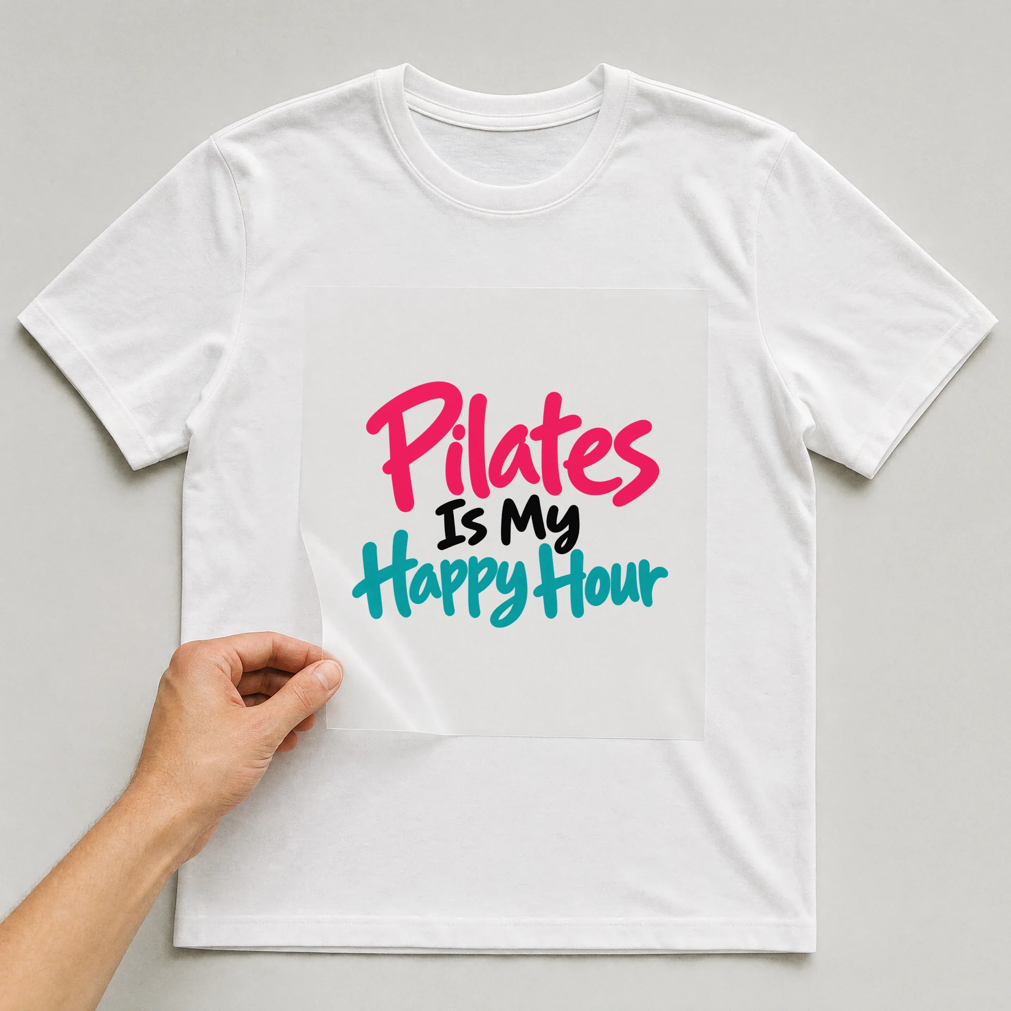 Bügelbild „Pilates Is My Happy Hour“ auf weißem T-Shirt, Folie wird aufgelegt