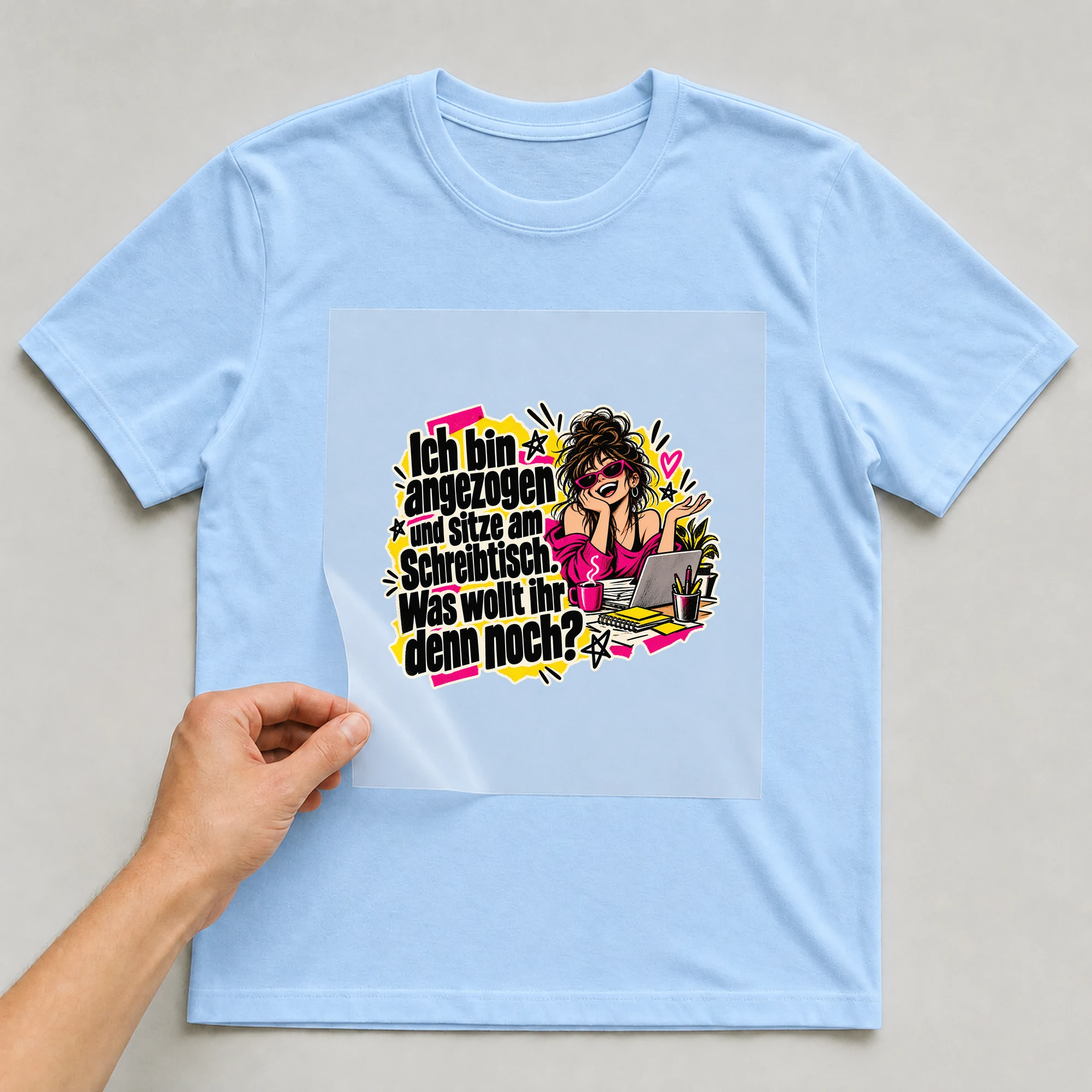 Bügelbild „Ich bin angezogen und sitze am Schreibtisch.“ auf babyblauem T-Shirt, Folie wird aufgelegt