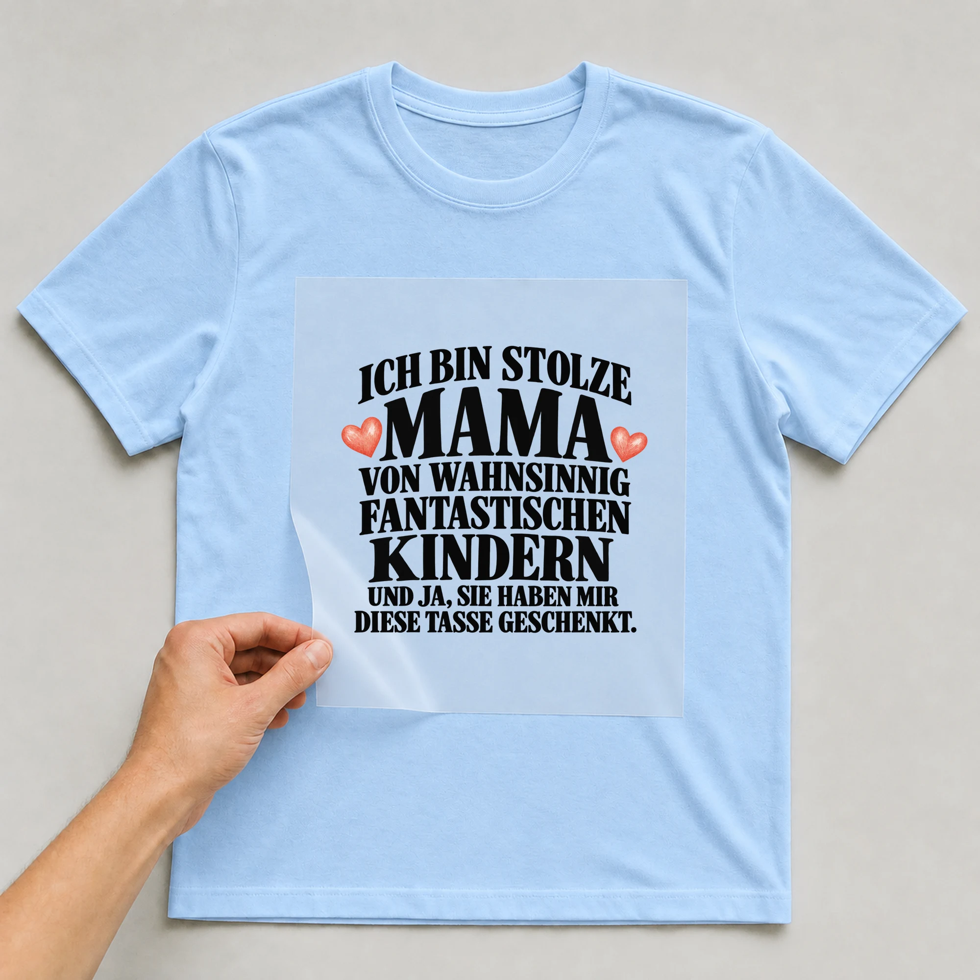 Bügelbild „Ich bin stolze Mama von wahnsinnig fantastischen Kindern und ja, sie haben mir“ auf babyblauem T-Shirt, Folie wird aufgelegt