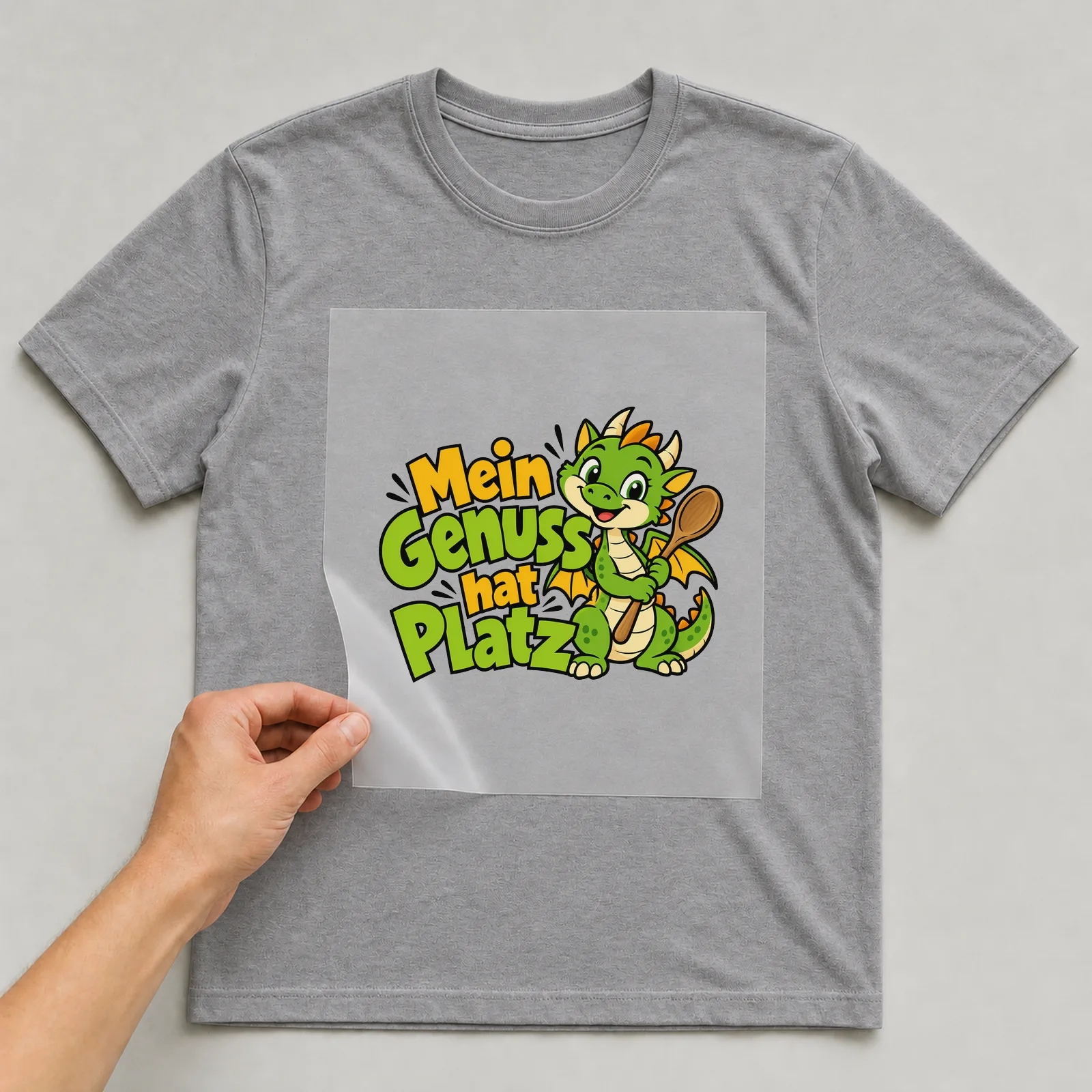 Bügelbild „Mein Genuss hat Platz“ auf grauem T-Shirt, Folie wird aufgelegt