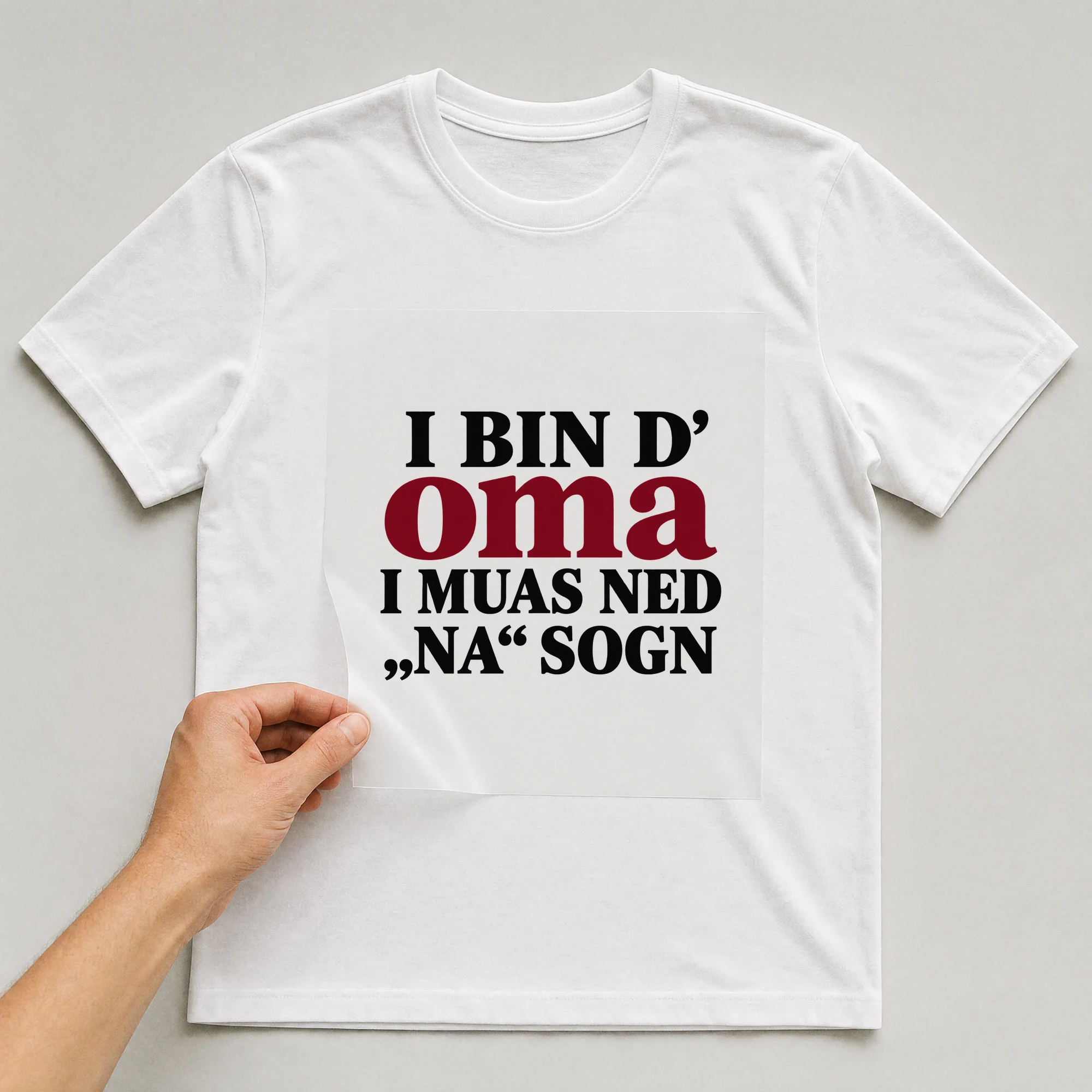Bügelbild „I Bin D' Oma I Muas Ned „na“ auf weißem T-Shirt, Folie wird aufgelegt