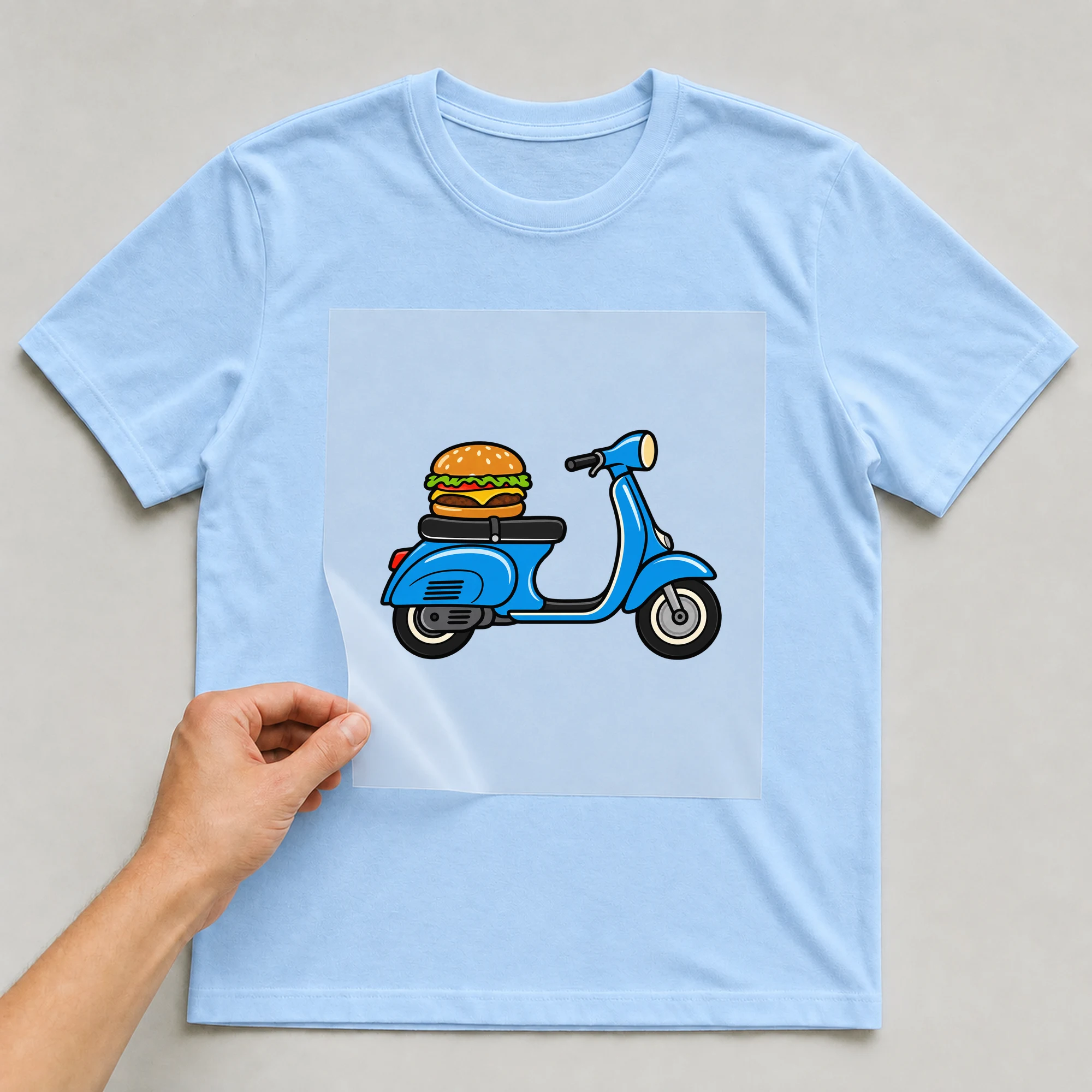 Bügelbild „Burger Scooter“ auf babyblauem T-Shirt, Folie wird aufgelegt