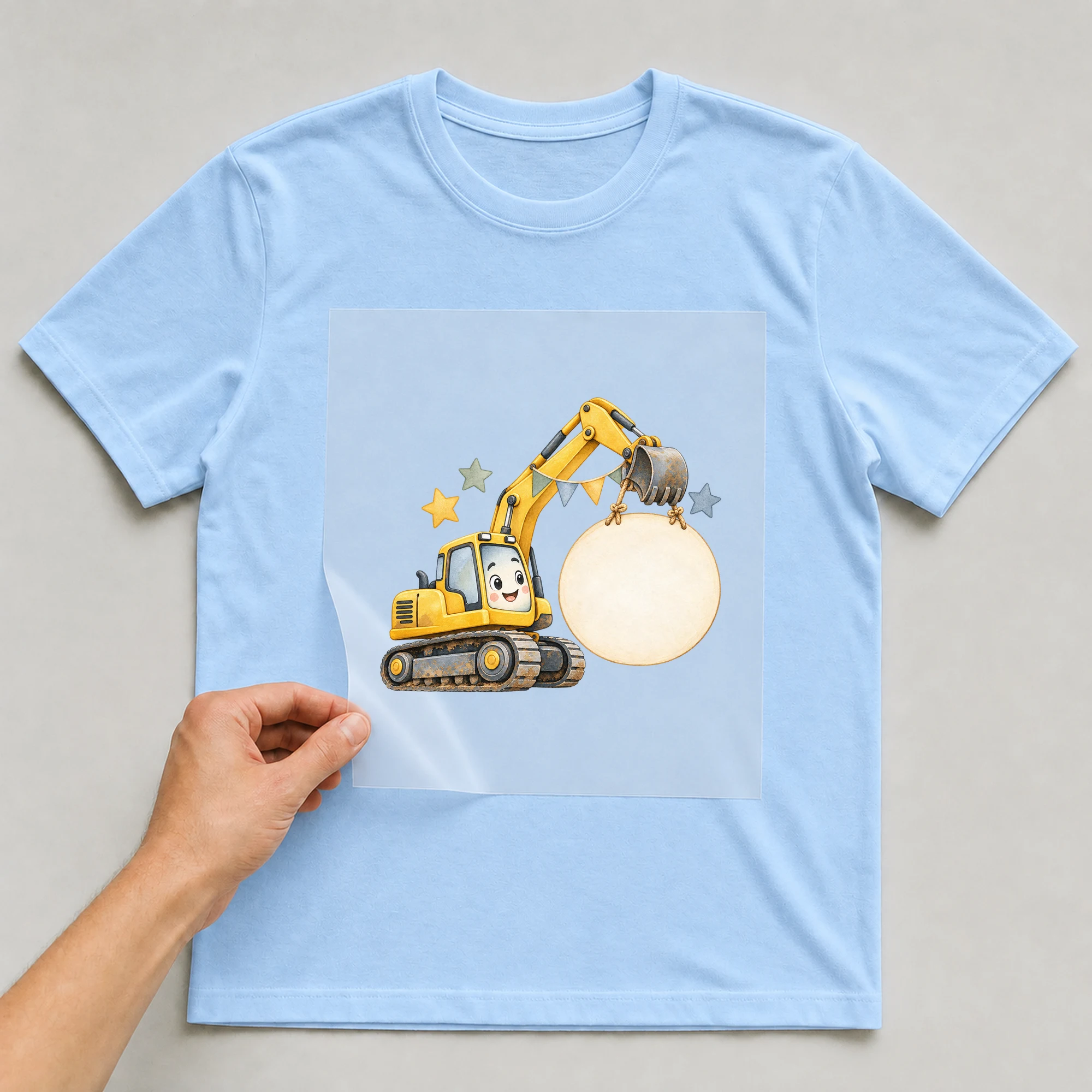 Bügelbild „Bagger im Aquarell-Stil“ auf babyblauem T-Shirt, Folie wird aufgelegt