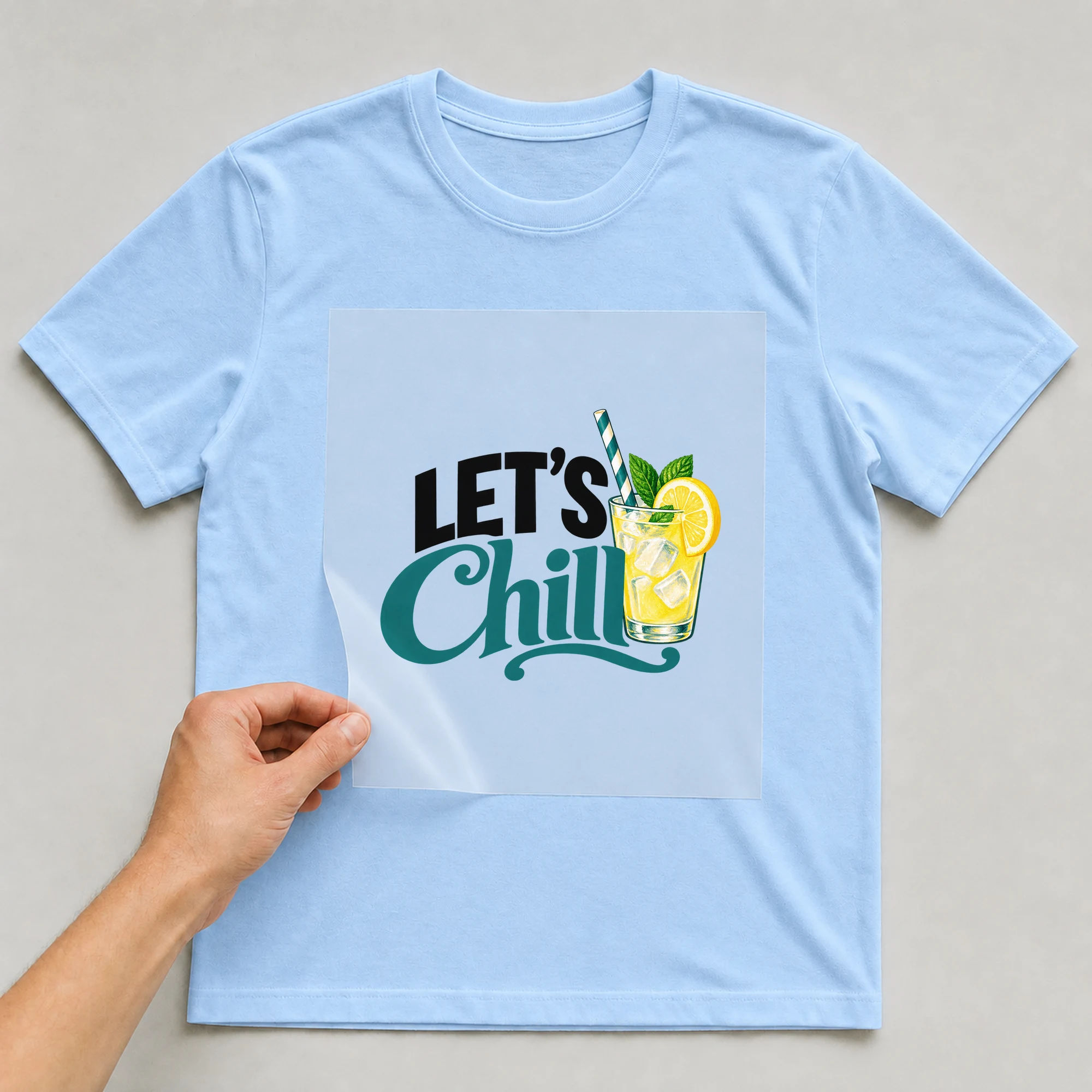 Bügelbild „LET'S Chill“ auf babyblauem T-Shirt, Folie wird aufgelegt