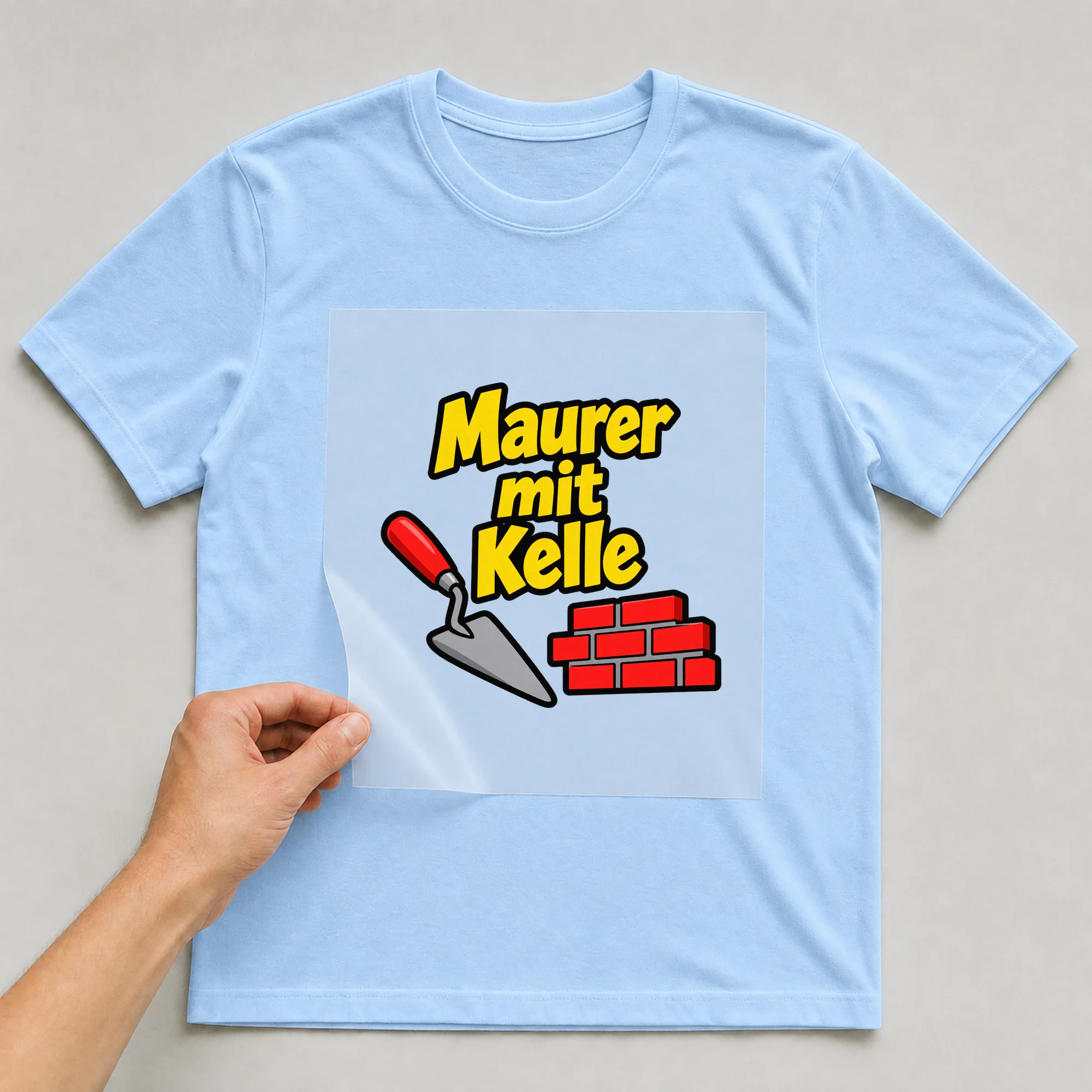 Bügelbild „Maurer mit Kelle“ auf babyblauem T-Shirt, Folie wird aufgelegt