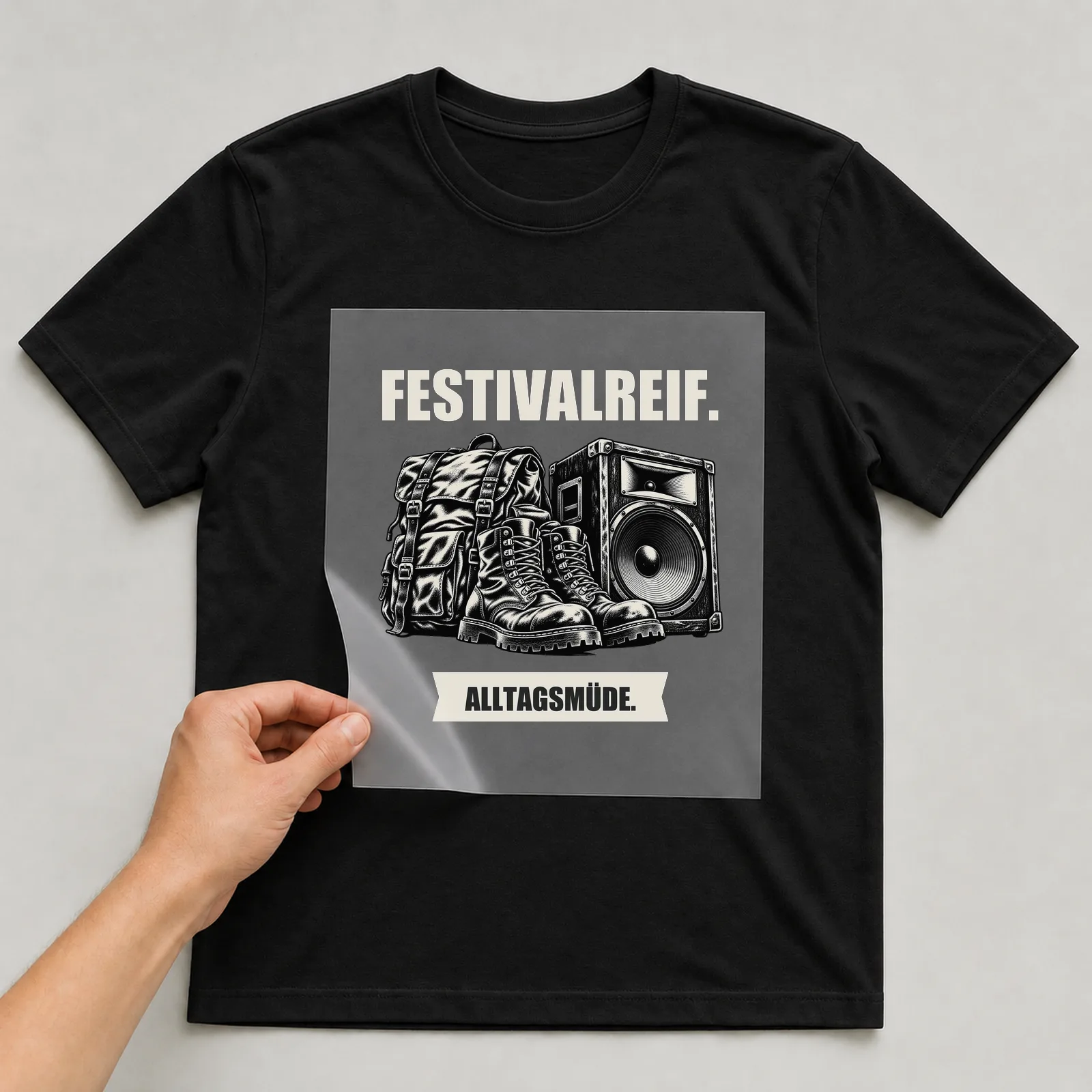 Bügelbild „Festivalreif. Alltagsmüde.“ auf schwarzem T-Shirt, Folie wird aufgelegt