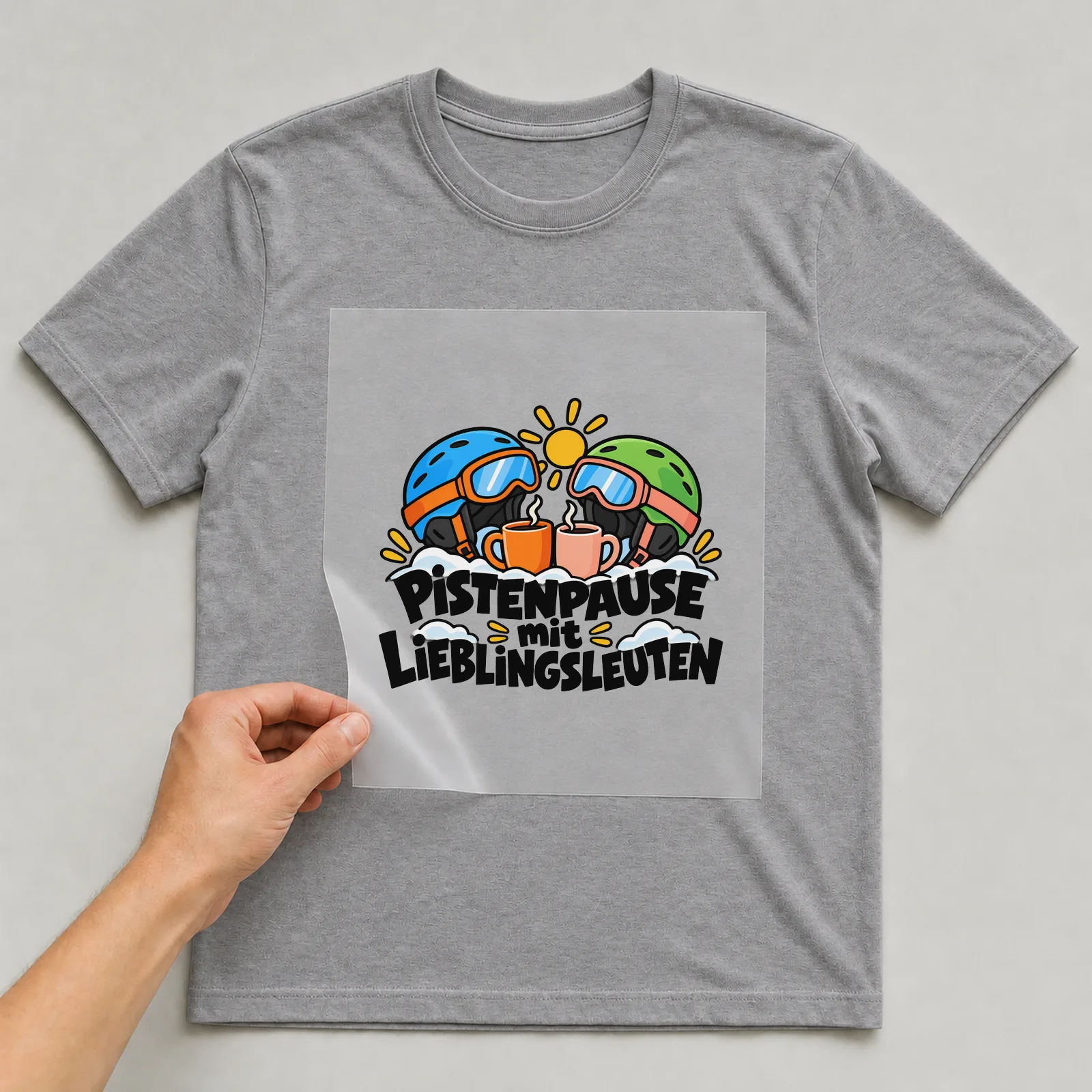 Bügelbild „PISTENPAUSE mit LIEBLINGSLEUTEN“ auf grauem T-Shirt, Folie wird aufgelegt