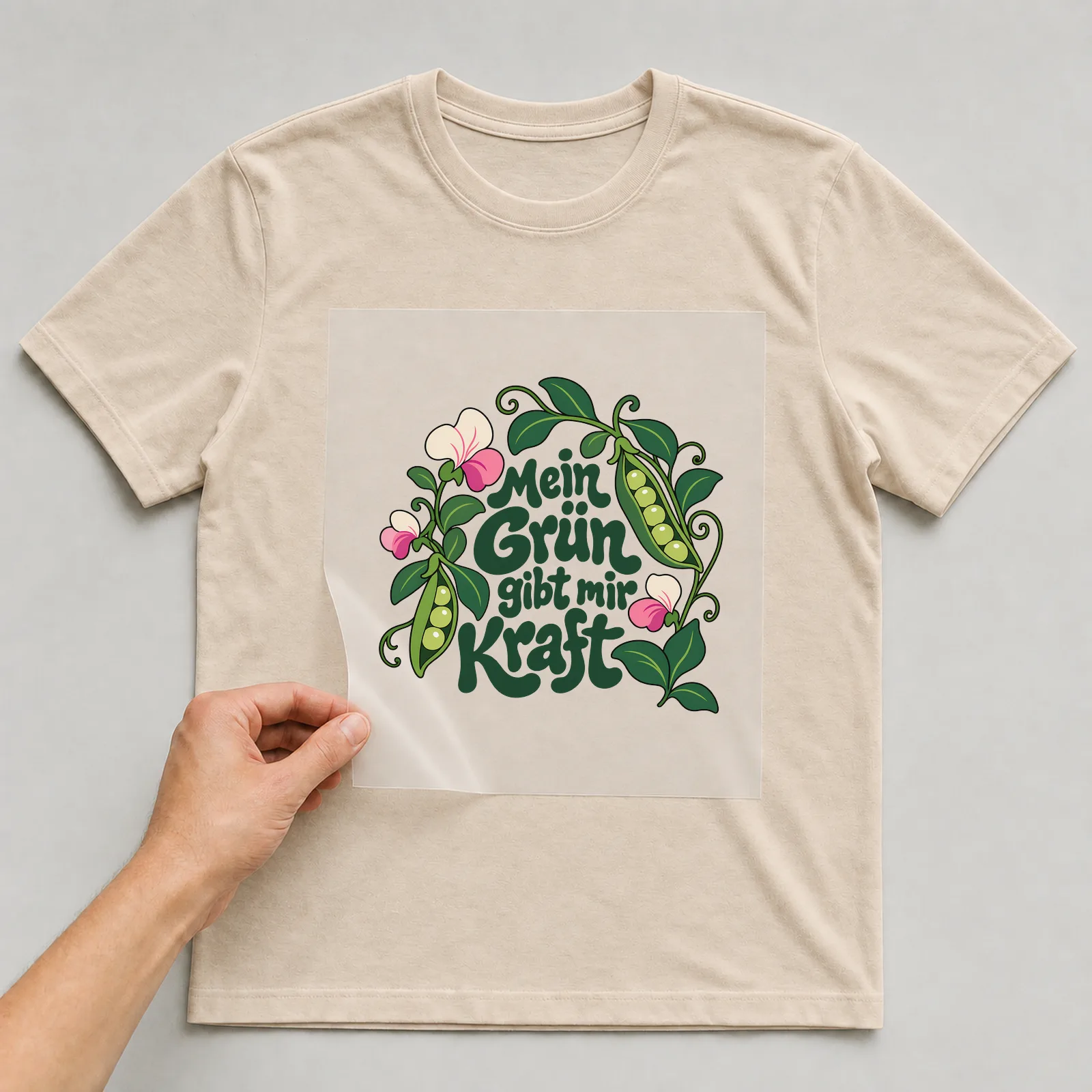 Bügelbild „Mein Grün gibt mir Kraft“ auf beigem T-Shirt, Folie wird aufgelegt