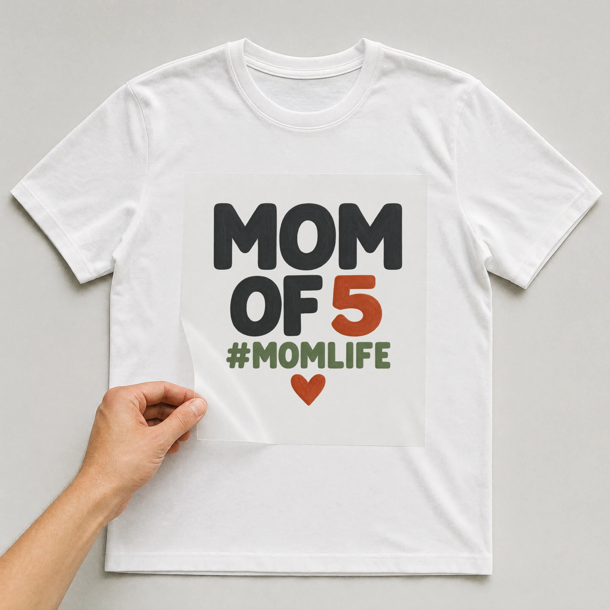 Bügelbild „Mom Of 5 #momlife“ auf weißem T-Shirt, Folie wird aufgelegt