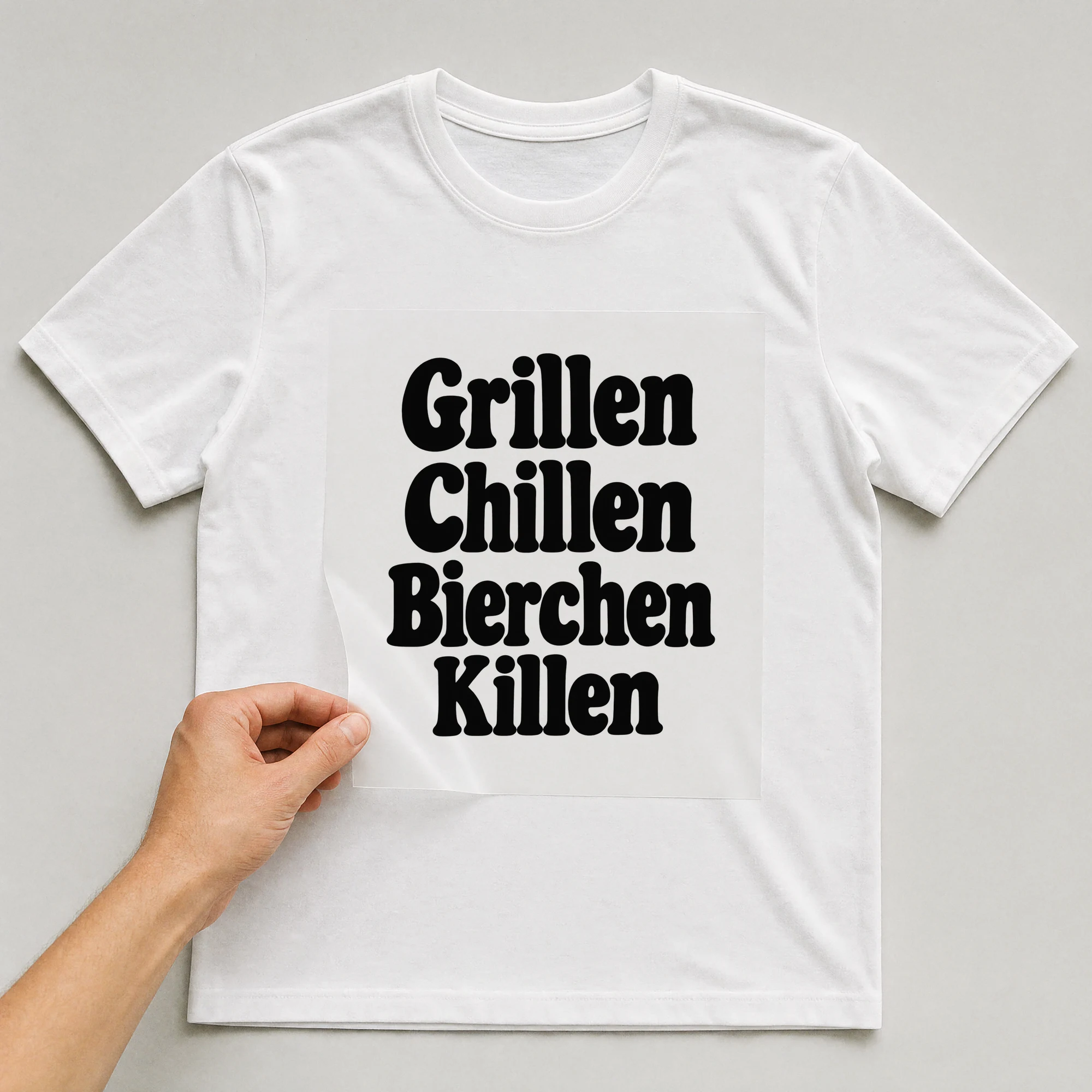 Bügelbild „Grillen Chillen Bierchen Killen“ auf weißem T-Shirt, Folie wird aufgelegt
