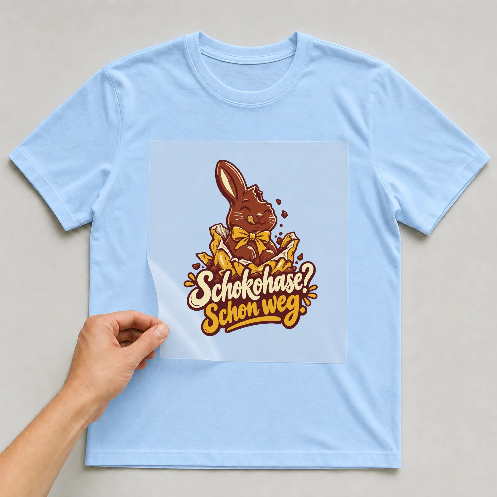 Bügelbild Schokohase? Schon weg. auf hellblauem T-Shirt, Folie wird aufgelegt