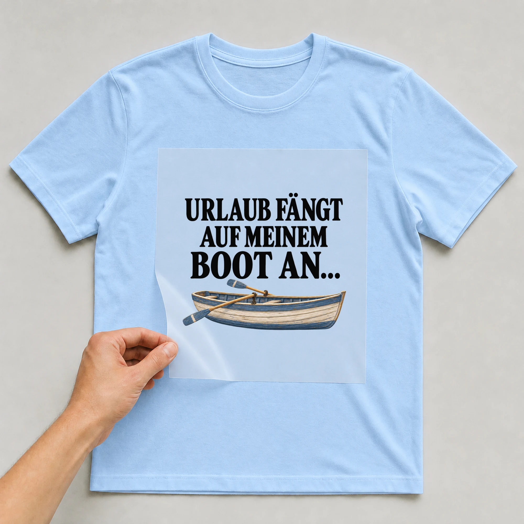 Bügelbild „Urlaub fängt auf meinem Boot an...“ auf babyblauem T-Shirt, Folie wird aufgelegt