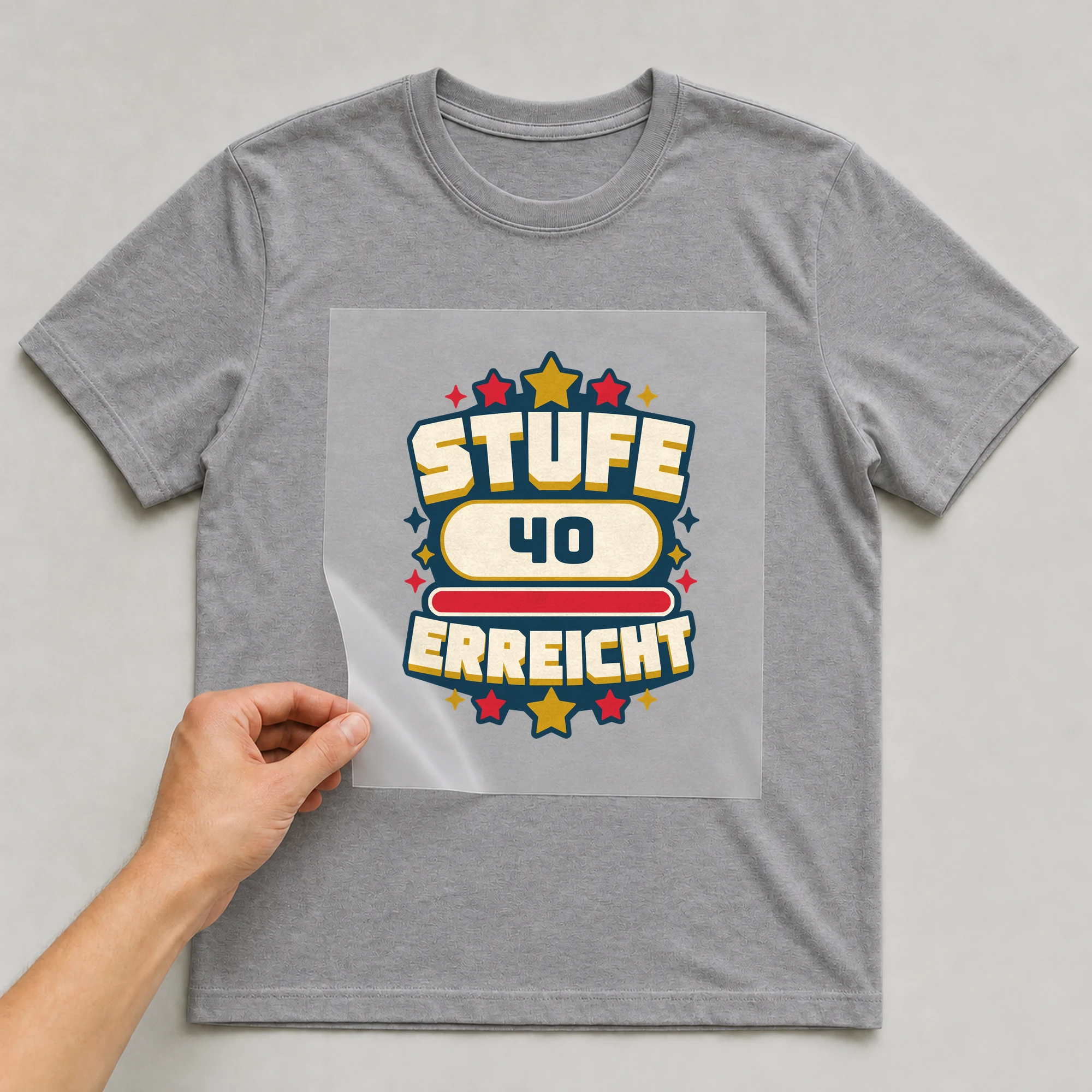 Bügelbild Stufe erreicht mit Zahl auf grauem T-Shirt, Folie wird aufgelegt