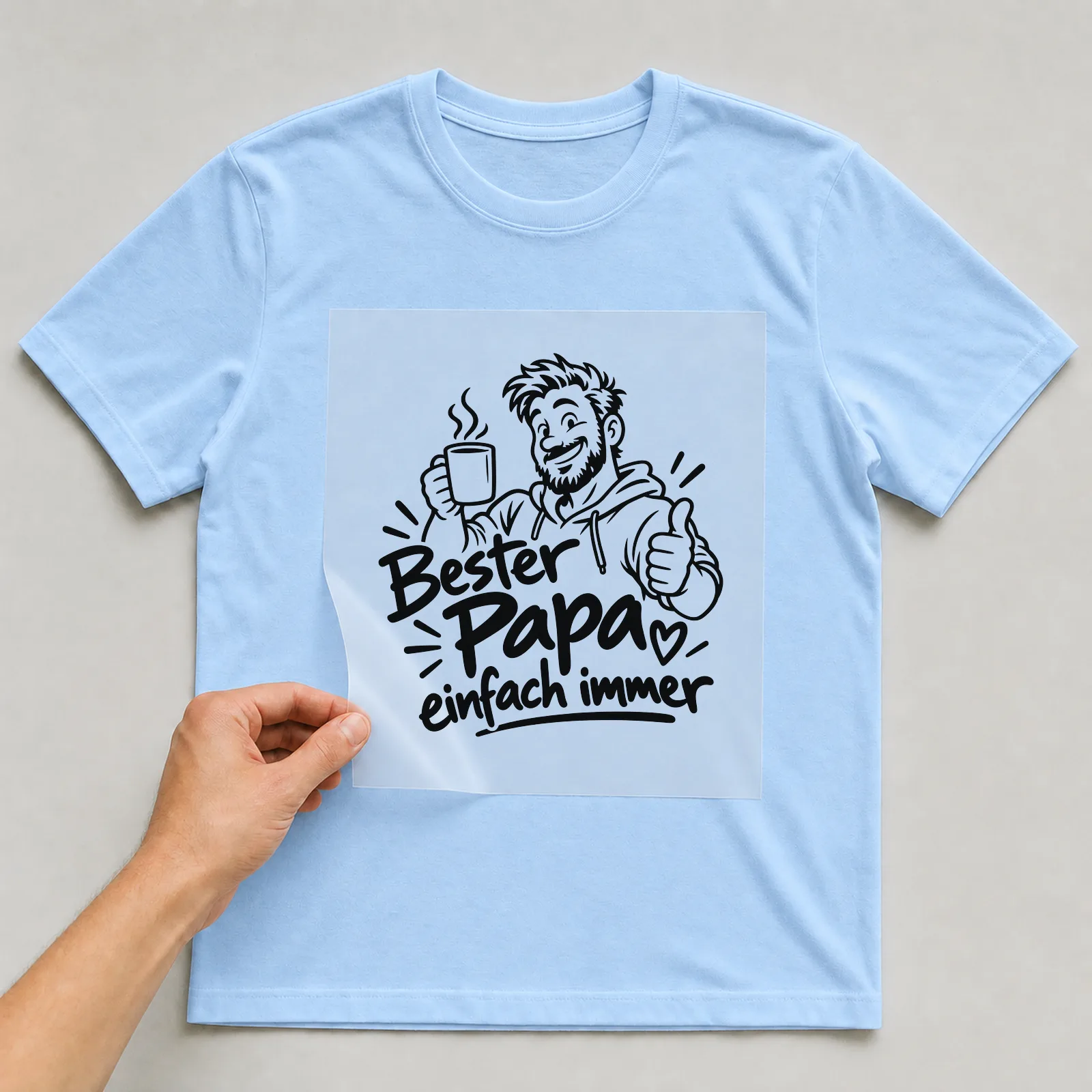 Bügelbild „Bester Papa einfach immer“ auf hellblauem T-Shirt, Folie wird aufgelegt