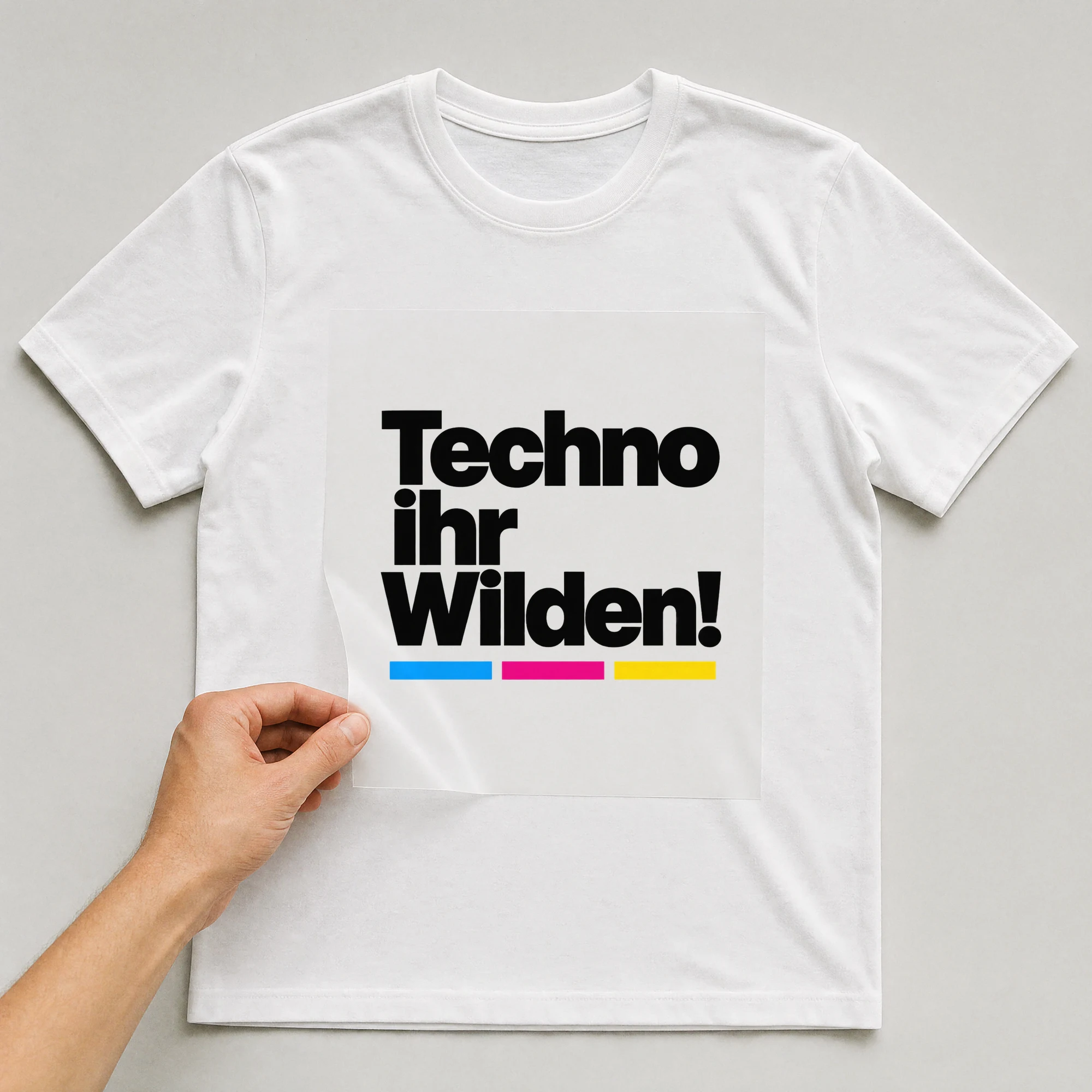 Bügelbild „Techno, ihr Wilden!“ auf weißem T-Shirt, Folie wird aufgelegt