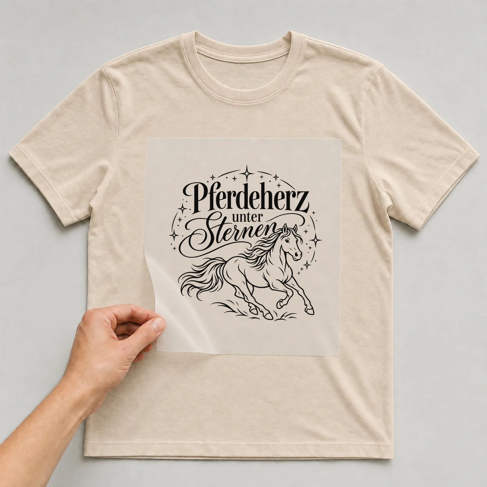 Bügelbild „Pferdeherz unter Sternen“ auf beigem T-Shirt, Folie wird aufgelegt