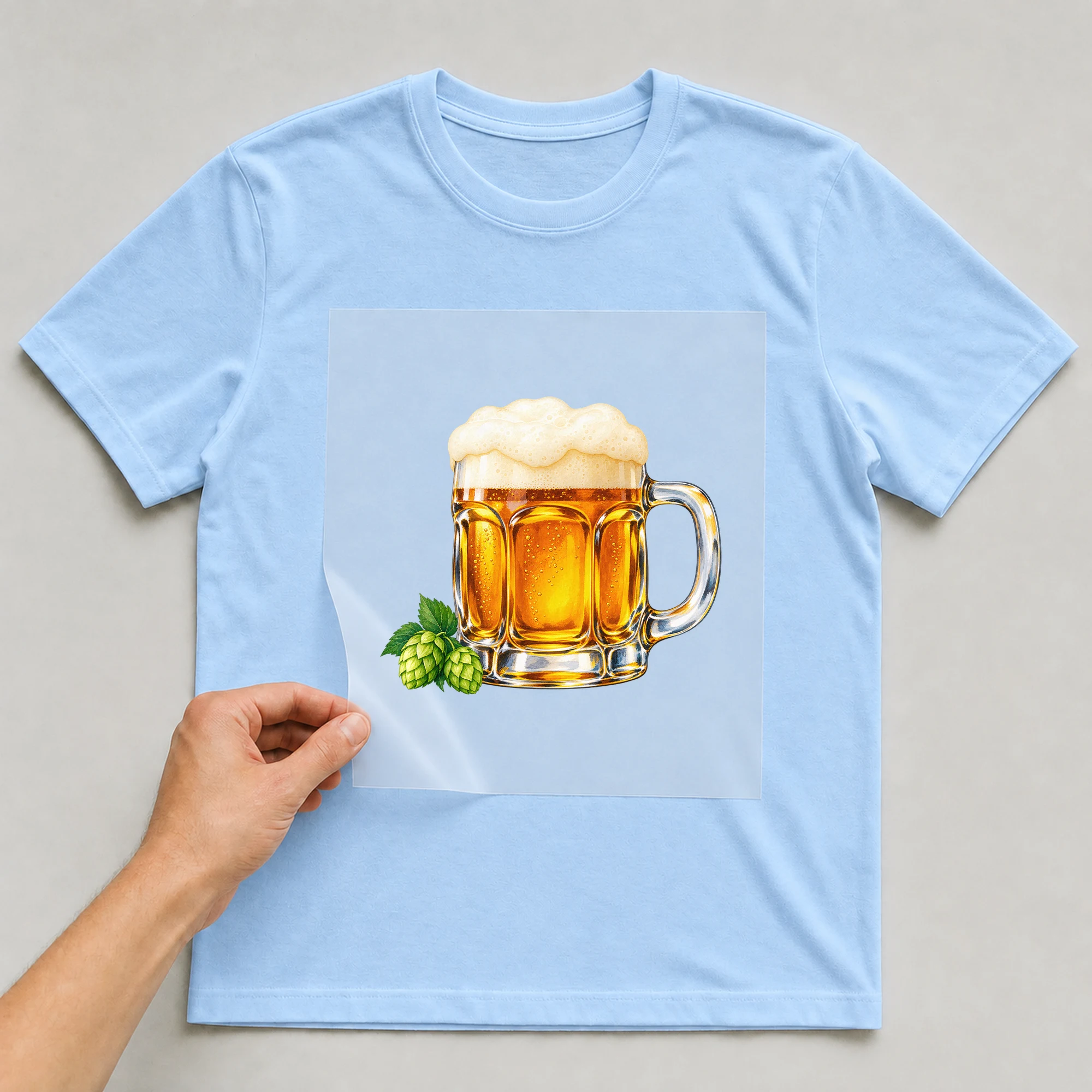 Bügelbild „Oktoberfest Maß“ auf babyblauem T-Shirt, Folie wird aufgelegt