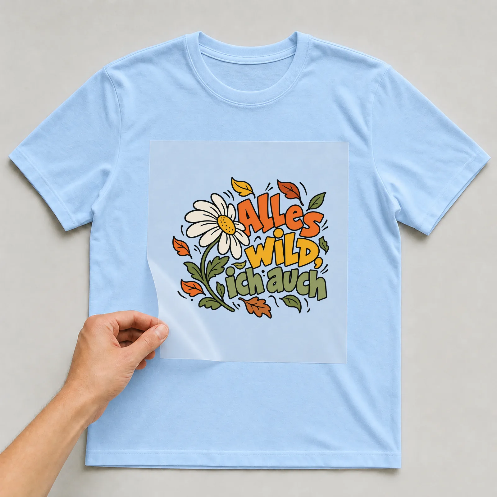 Bügelbild „Alles wild, ich auch“ auf hellblauem T-Shirt, Folie wird aufgelegt