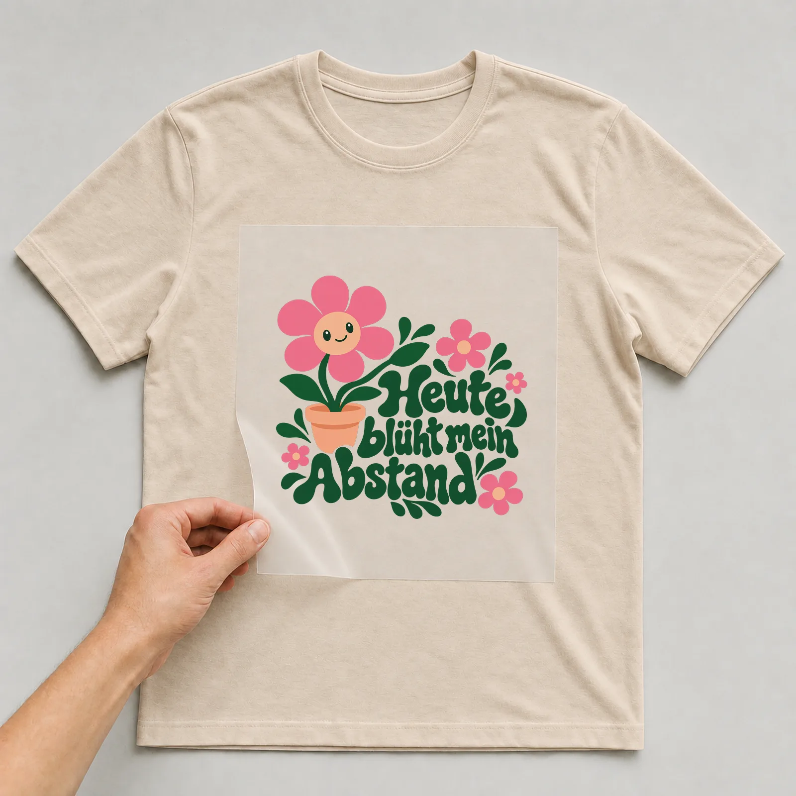 Bügelbild „Heute blüht mein Abstand“ auf beigem T-Shirt, Folie wird aufgelegt