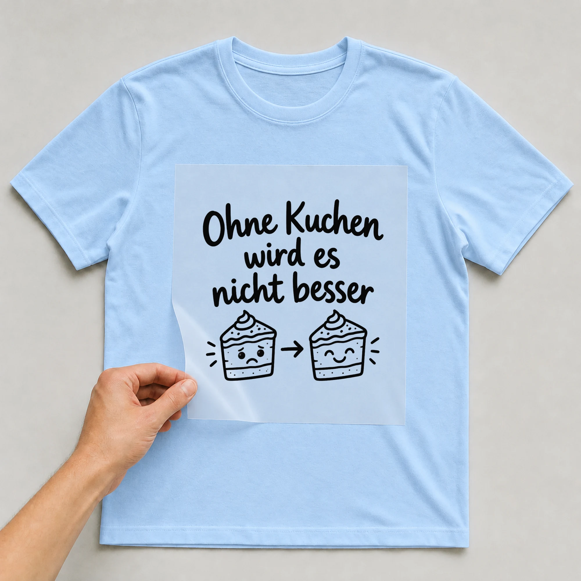 Bügelbild „Ohne Kuchen wird es nicht besser“ auf babyblauem T-Shirt, Folie wird aufgelegt
