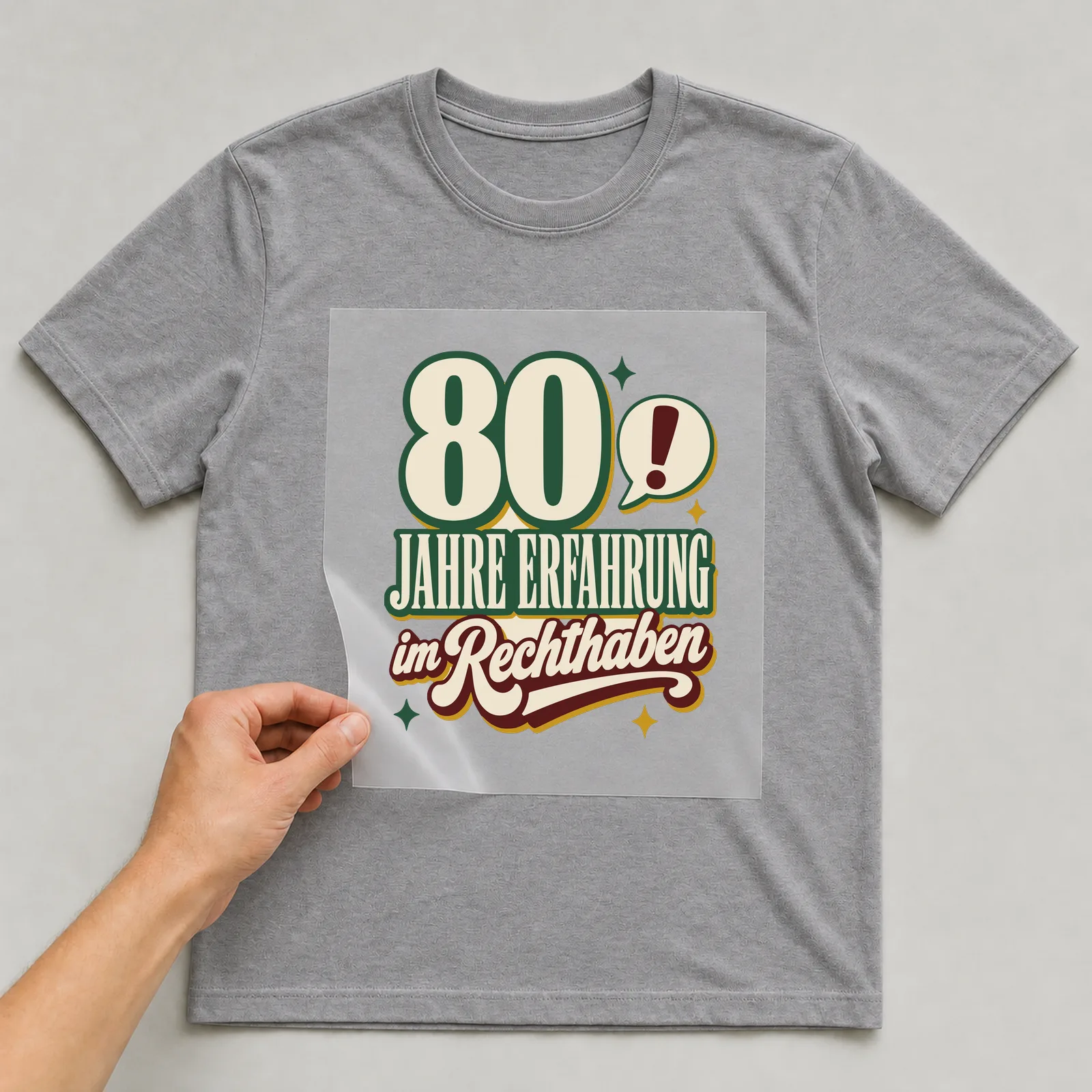 Bügelbild 80 Jahre Erfahrung im Rechthaben auf grauem T-Shirt, Folie wird aufgelegt
