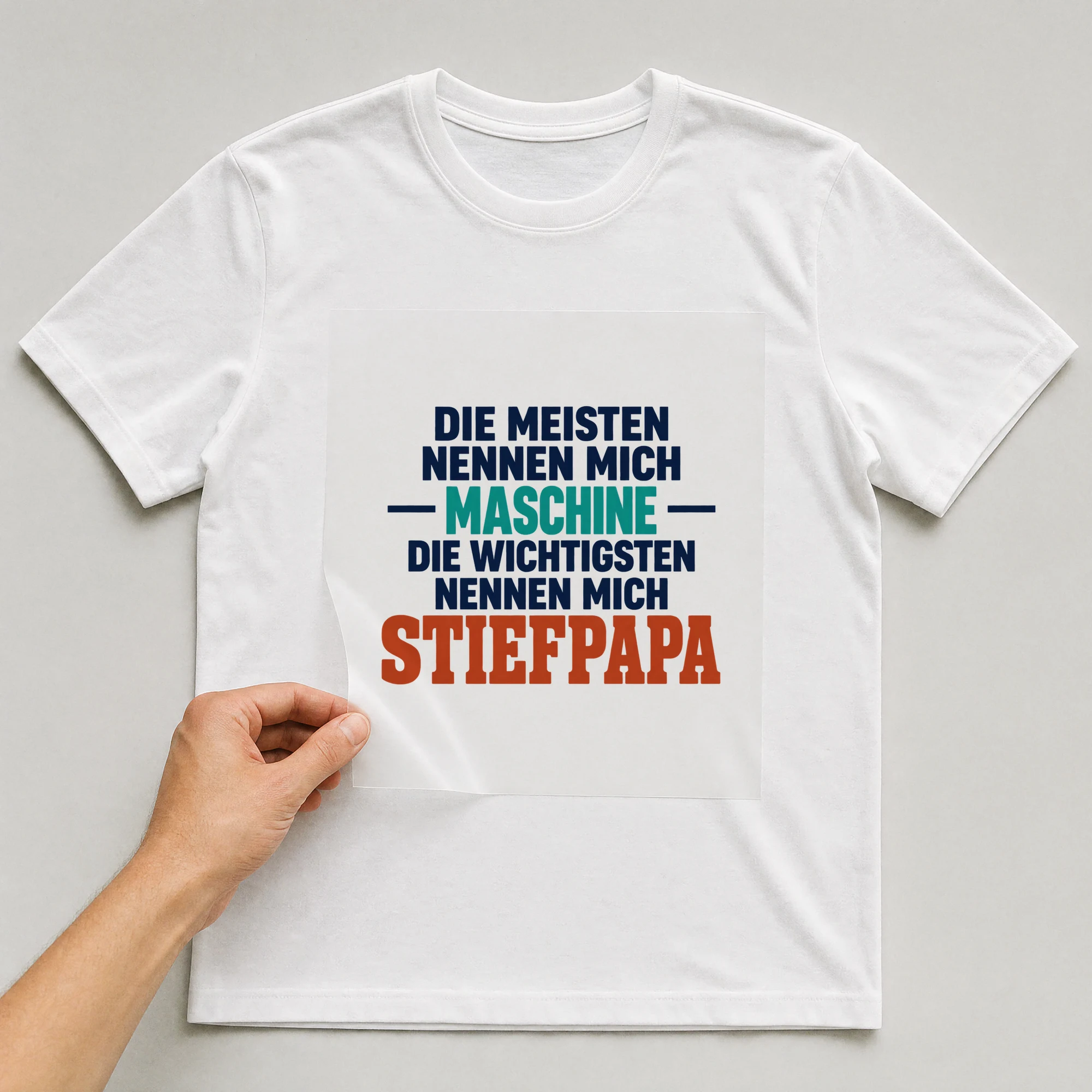 Bügelbild „Die meisten Nennen mich Maschine die wichtigsten Nennen mich Stiefpapa“ auf weißem T-Shirt, Folie wird aufgelegt