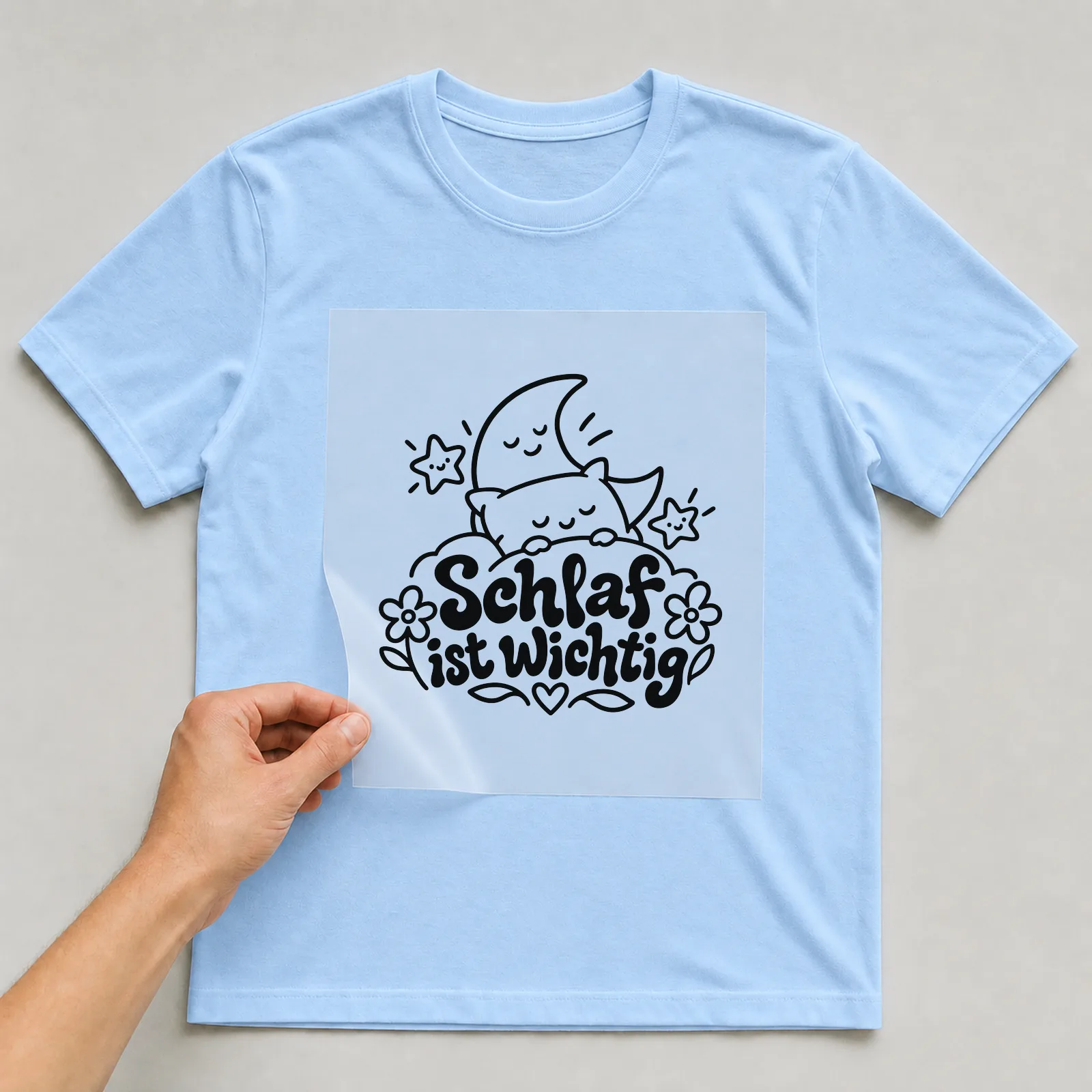 Bügelbild „Schlaf ist wichtig“ auf hellblauem T-Shirt, Folie wird aufgelegt