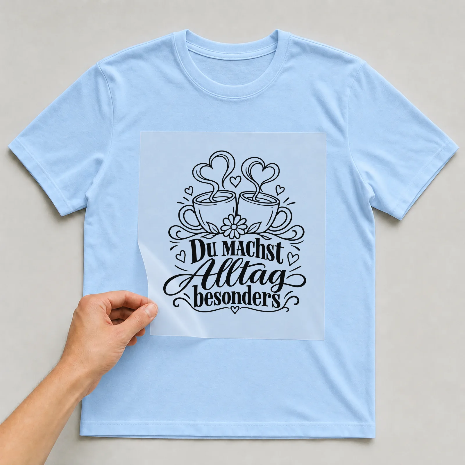 Bügelbild „Du machst Alltag besonders“ auf hellblauem T-Shirt, Folie wird aufgelegt